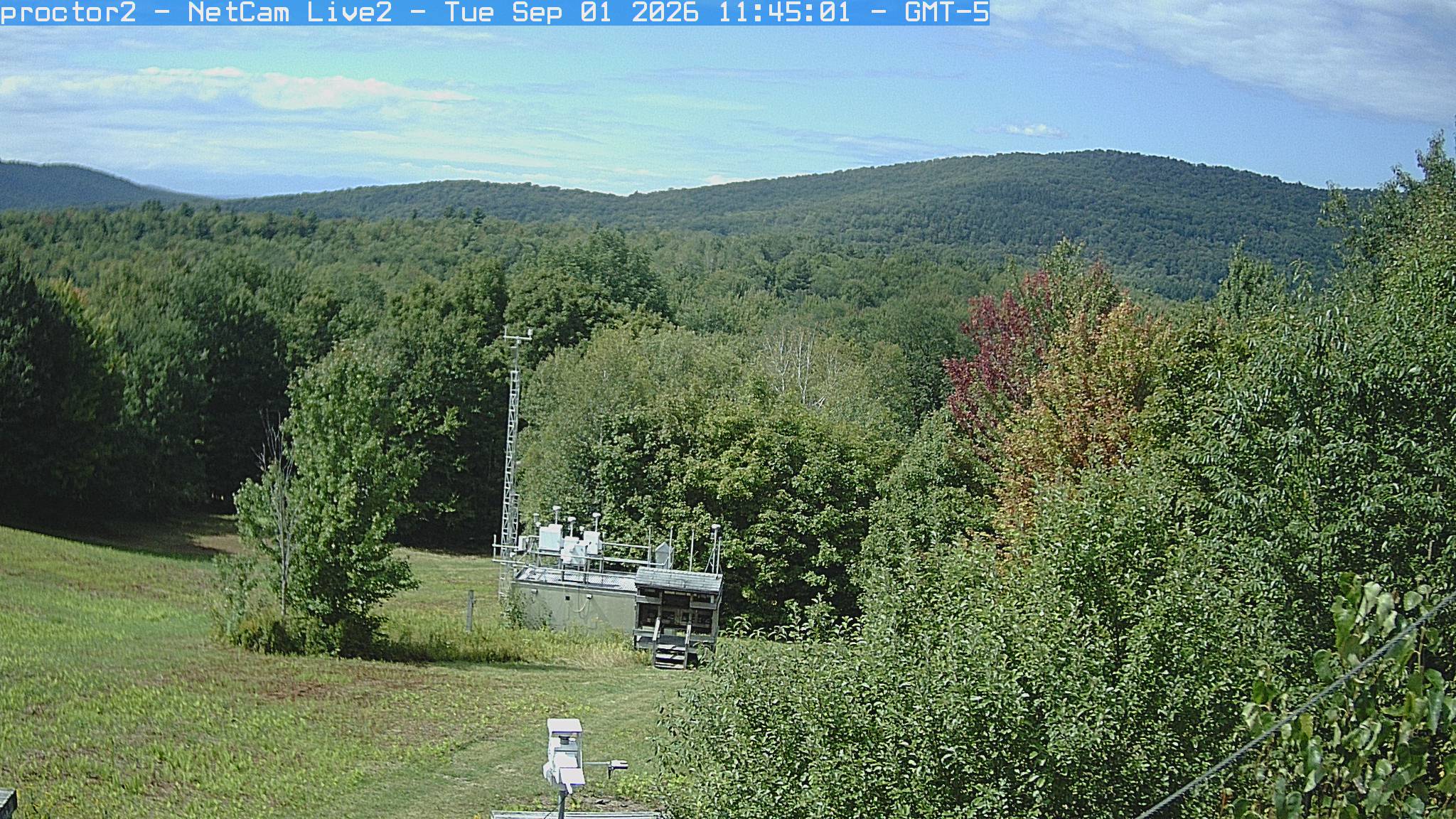 Wooded hills rise beyond an open foreground with research instruments.