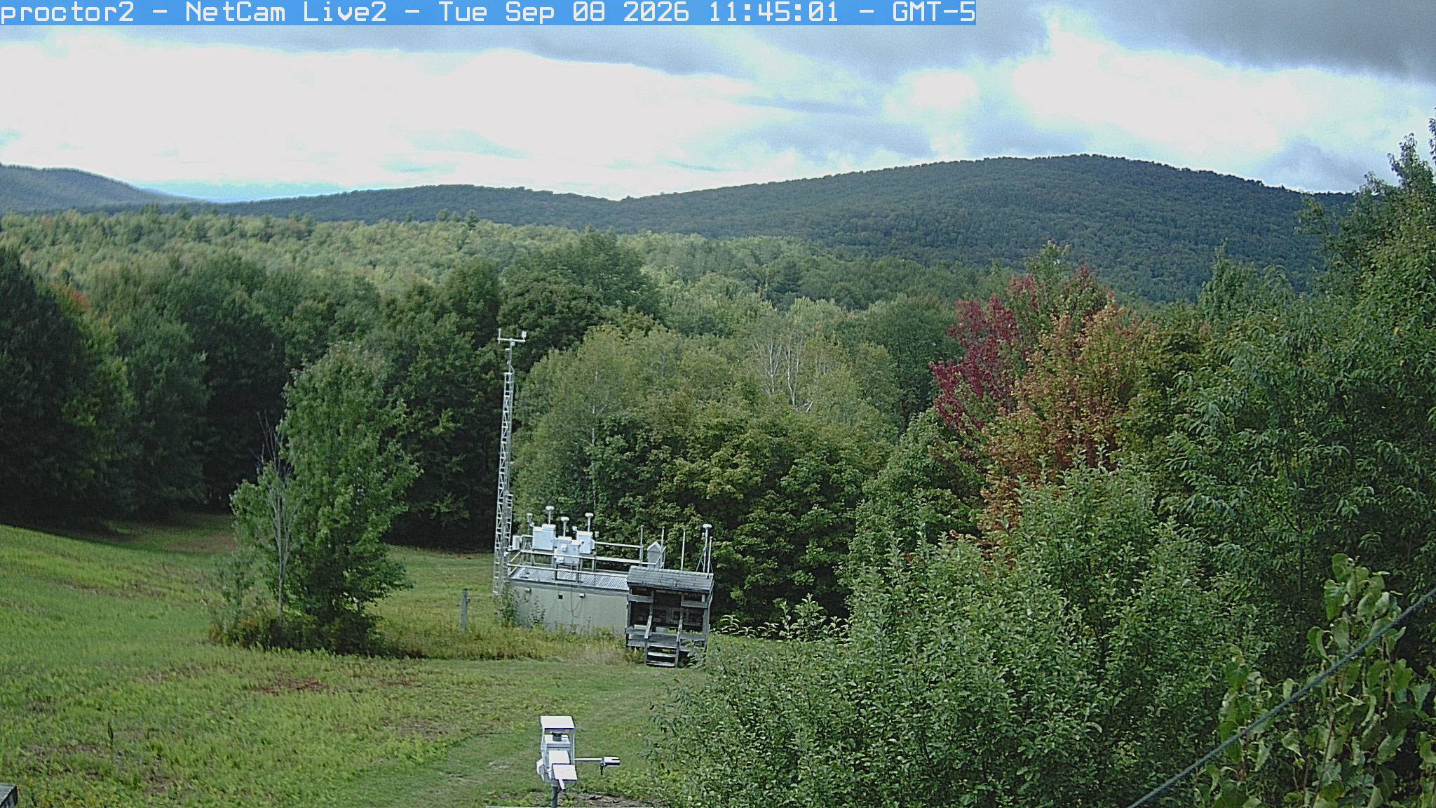 Wooded hills rise beyond an open foreground with research instruments.