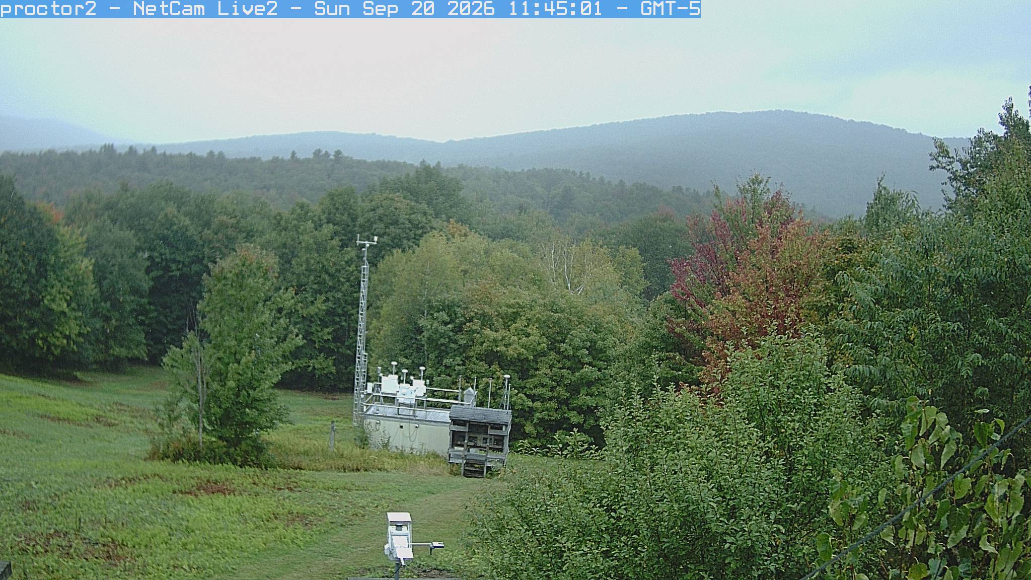Wooded hills rise beyond an open foreground with research instruments.