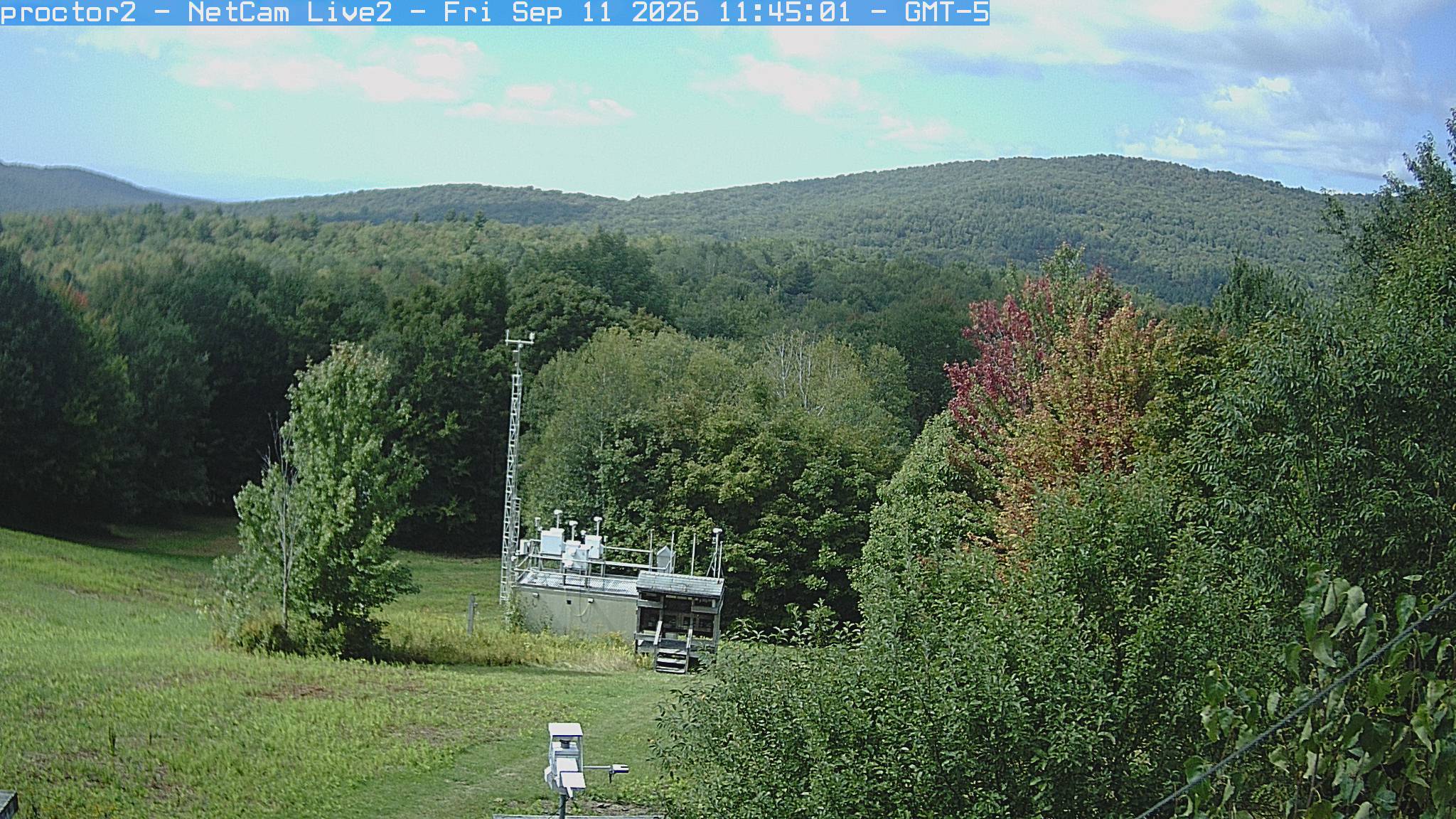 Wooded hills rise beyond an open foreground with research instruments.