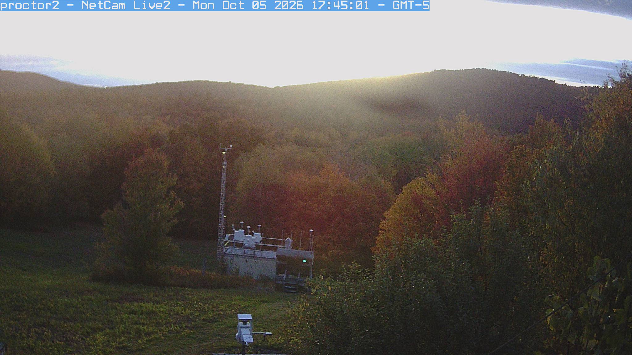 Wooded hills rise beyond an open foreground with research instruments.