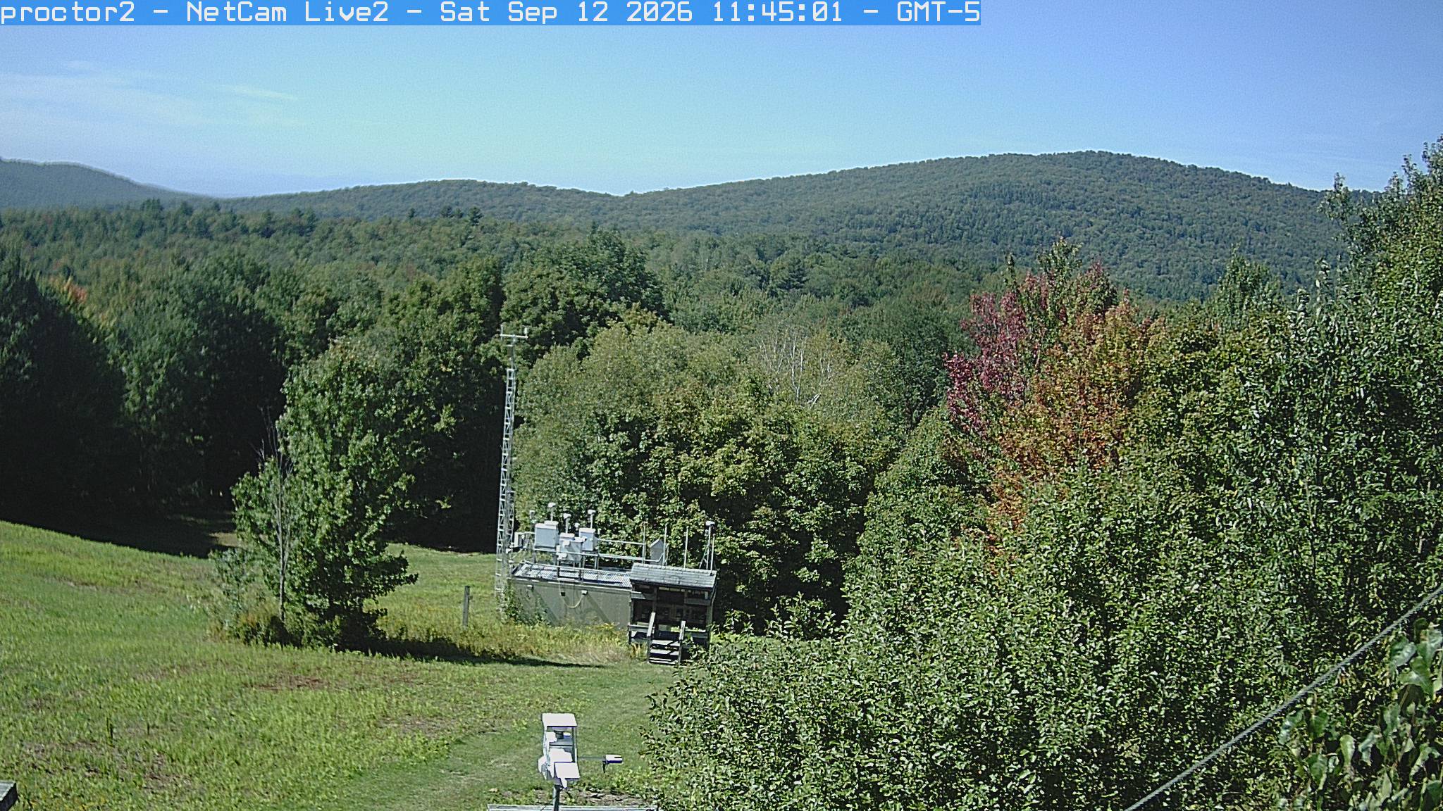 Wooded hills rise beyond an open foreground with research instruments.