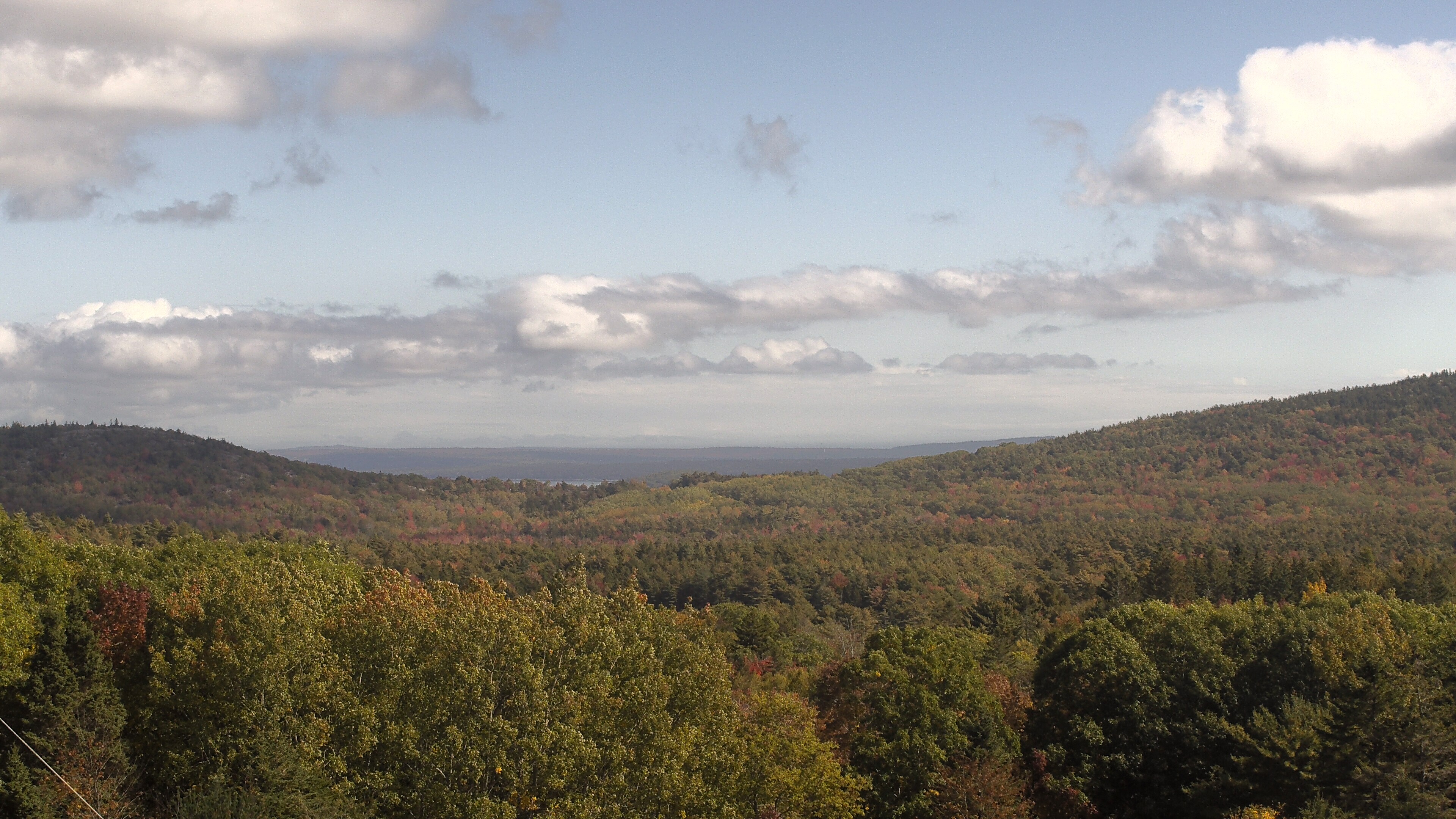 A wooded valley opens toward distant water, seen from McFarland Hill.
