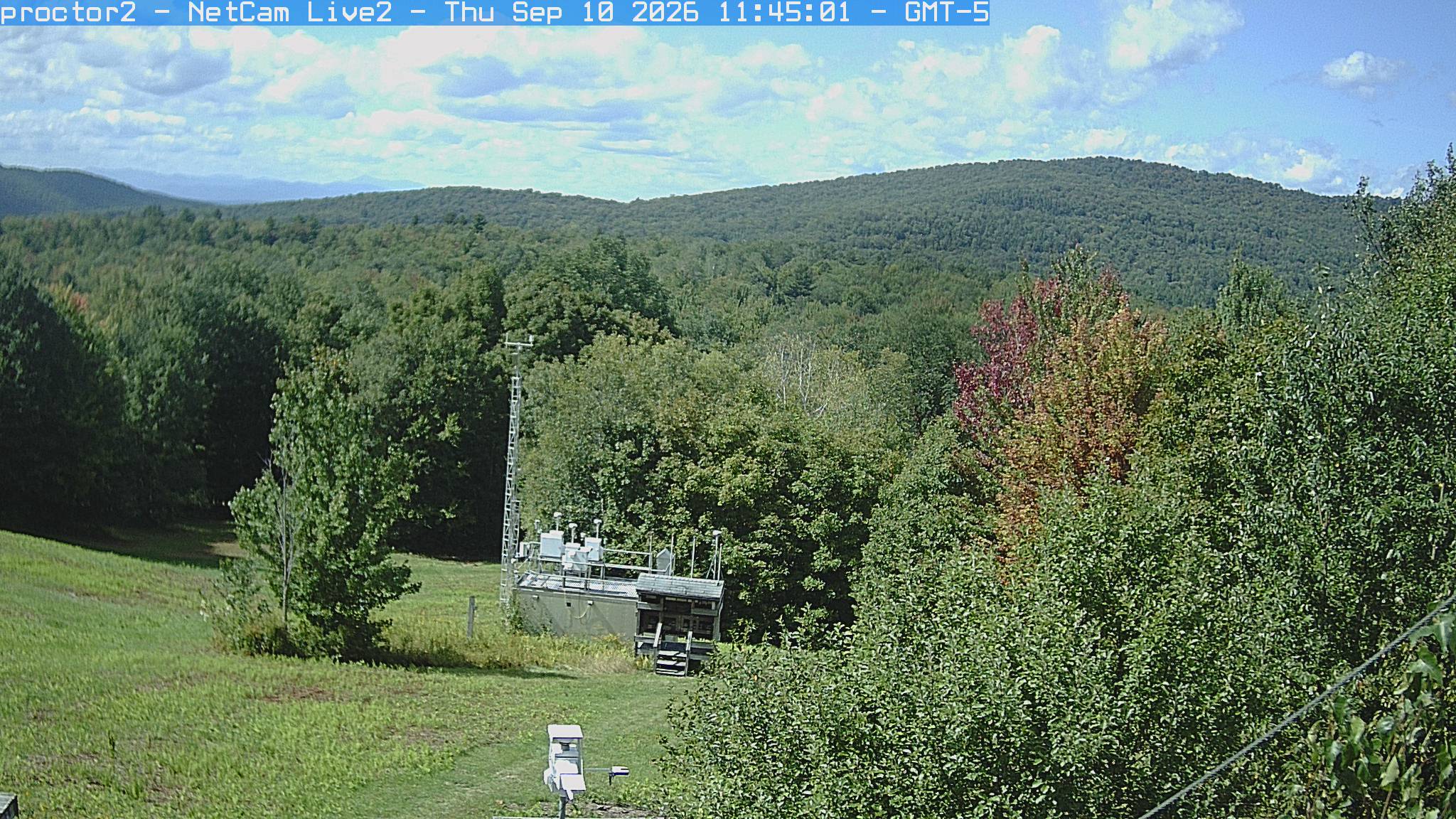 Wooded hills rise beyond an open foreground with research instruments.
