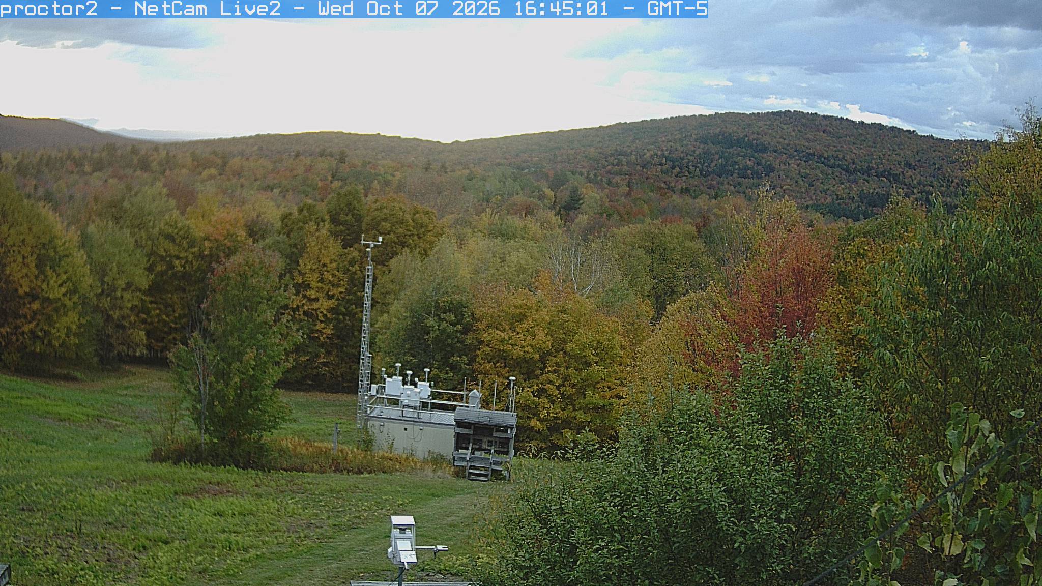 Wooded hills rise beyond an open foreground with research instruments.