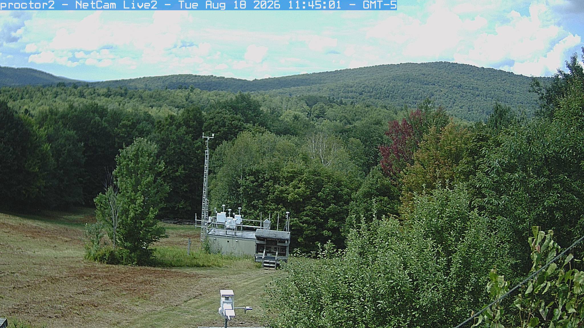 Wooded hills rise beyond an open foreground with research instruments.
