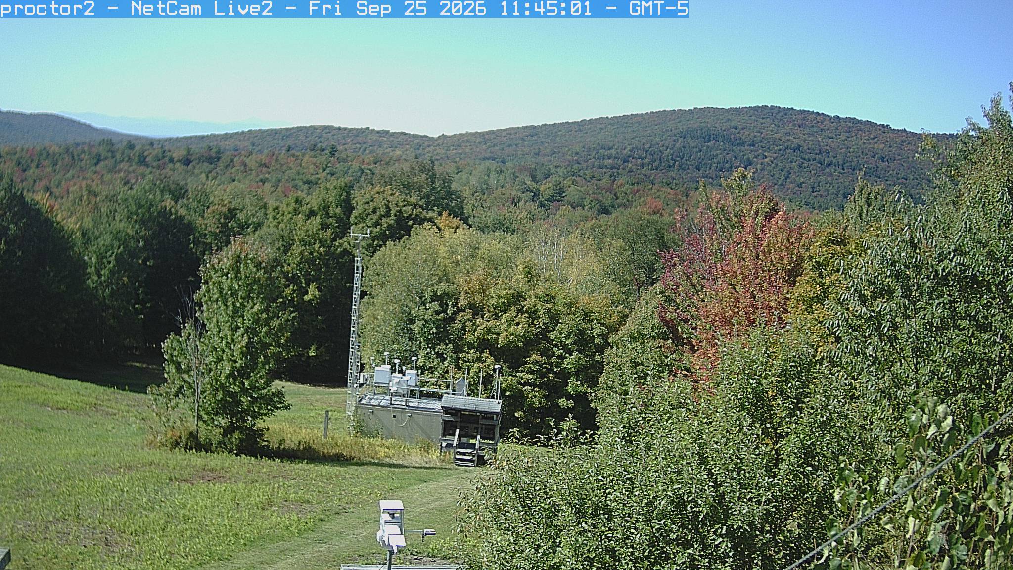 Wooded hills rise beyond an open foreground with research instruments.