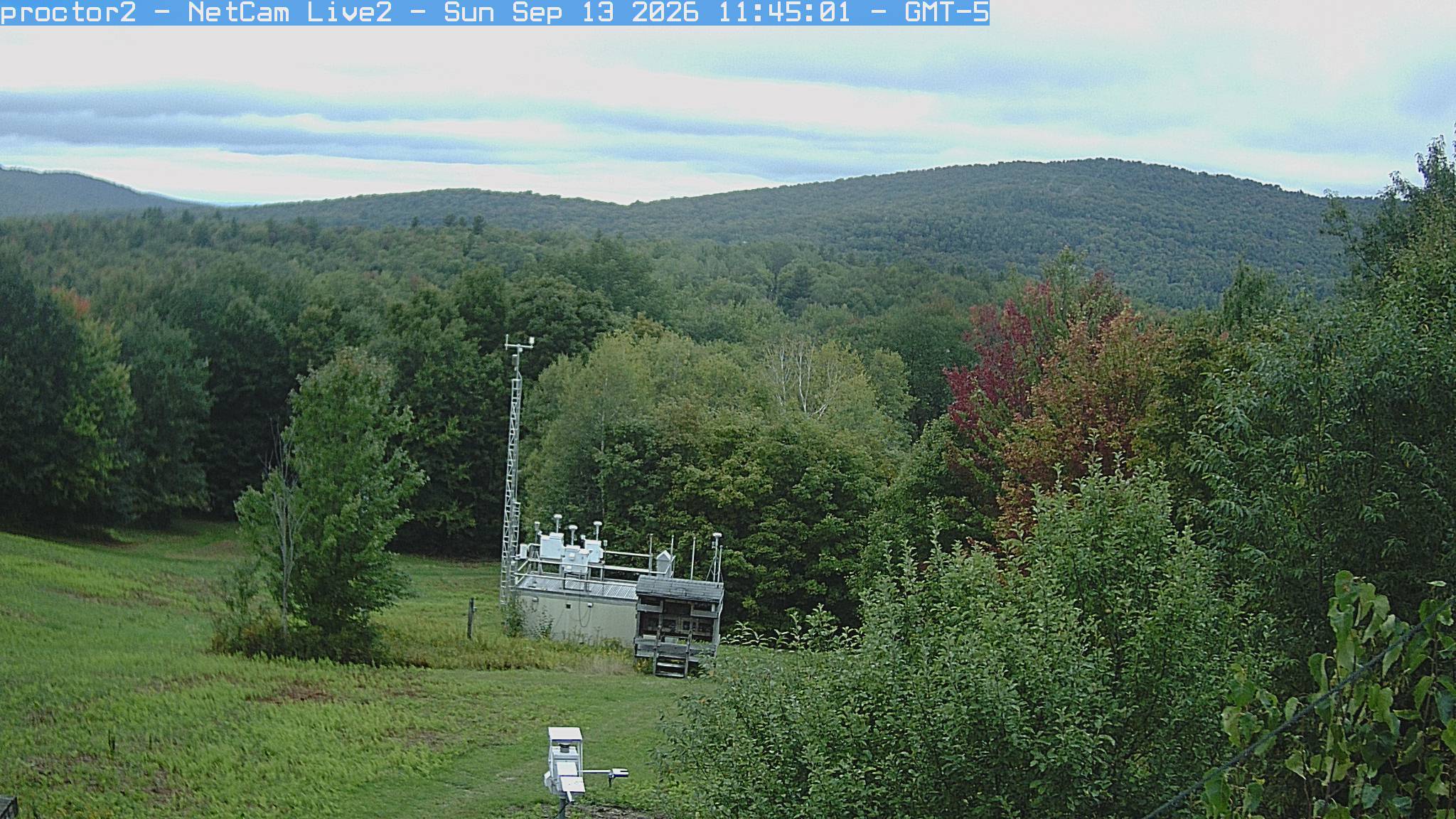 Wooded hills rise beyond an open foreground with research instruments.