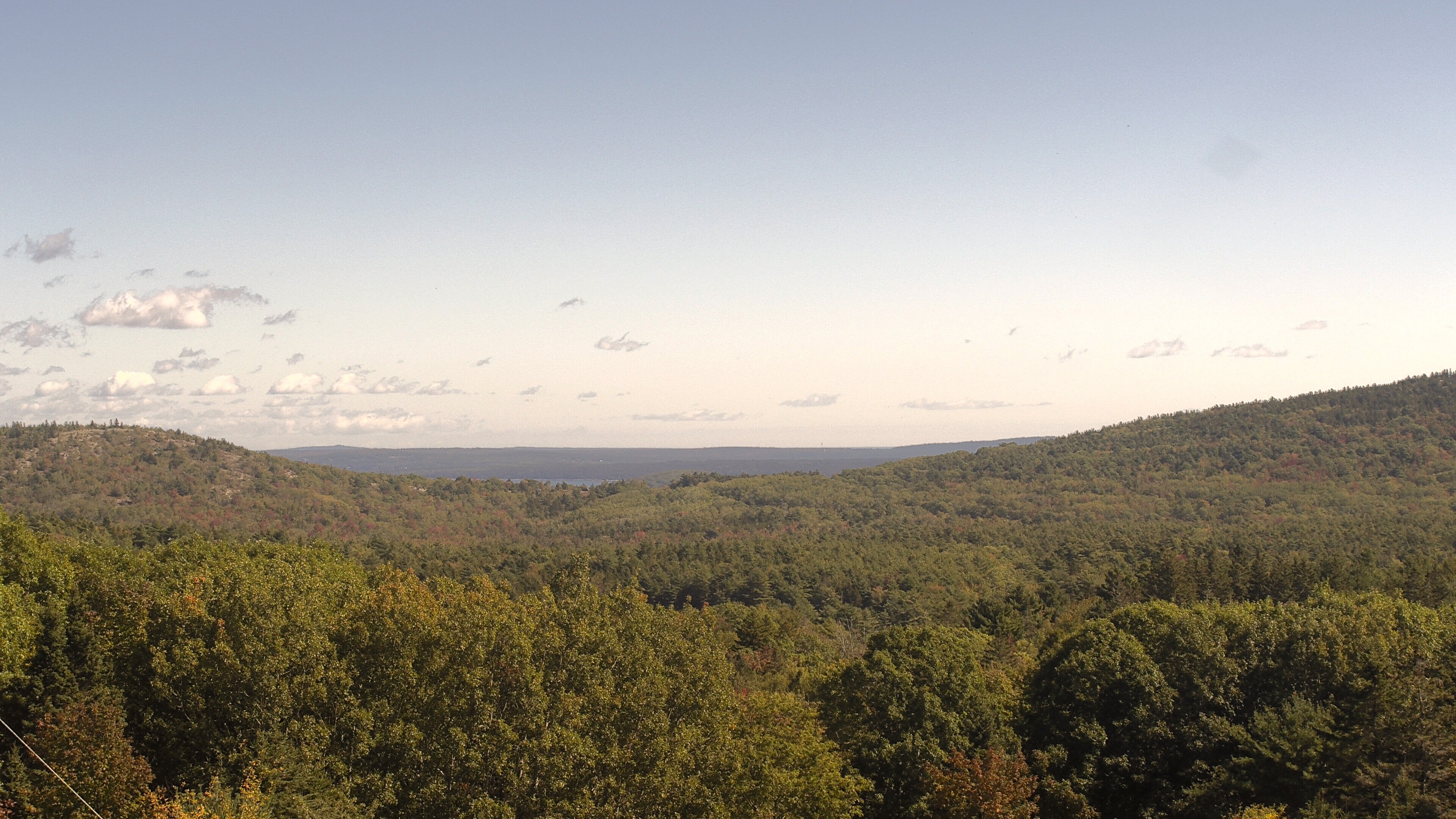 A wooded valley opens toward distant water, seen from McFarland Hill.