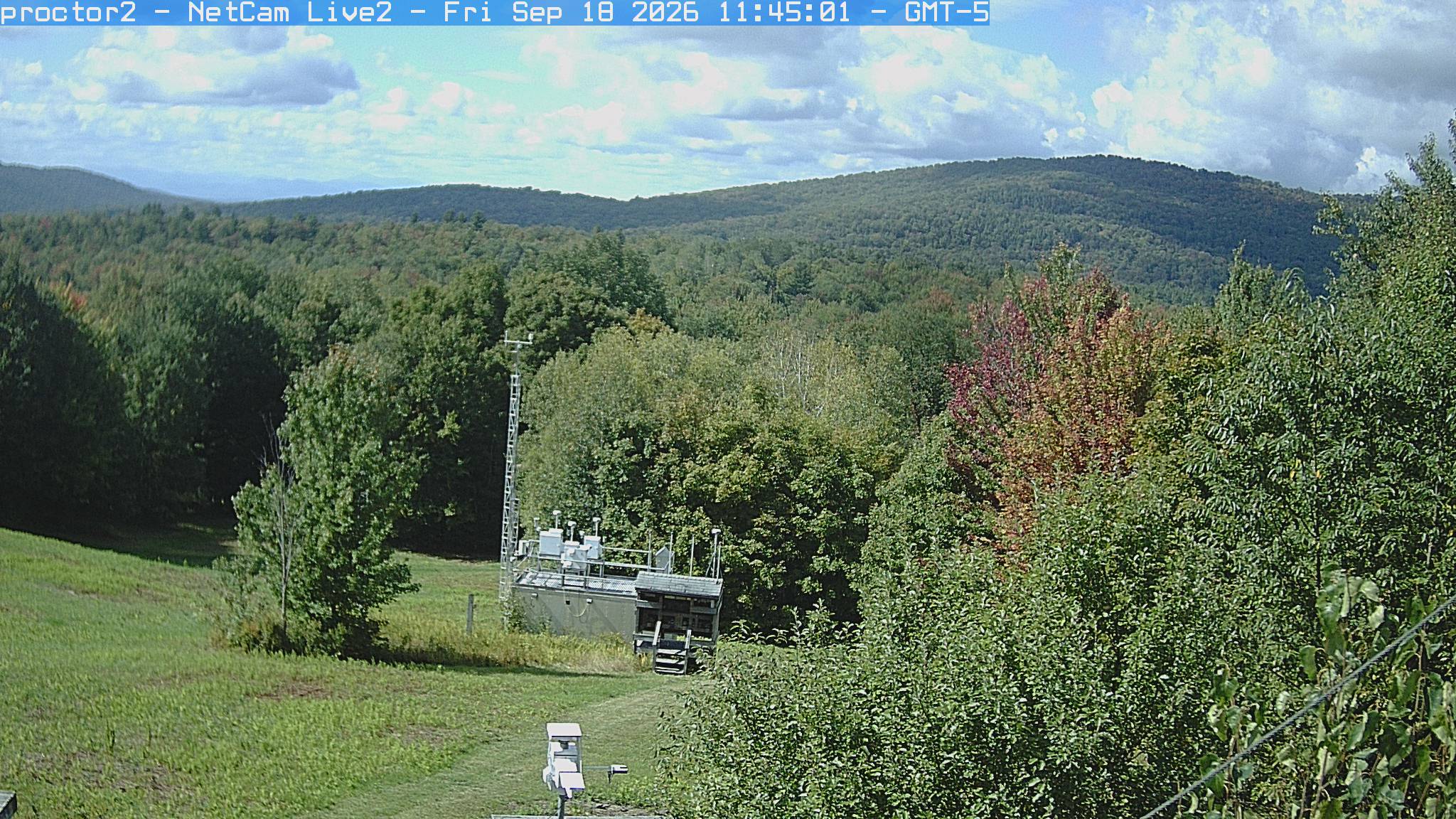 Wooded hills rise beyond an open foreground with research instruments.