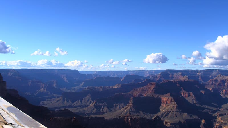 The Grand Canyon’s red and buff cliffs and buttes stretch to the North Rim under an open sky.