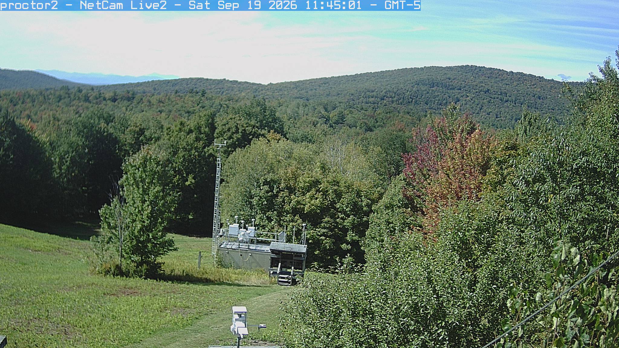 Wooded hills rise beyond an open foreground with research instruments.