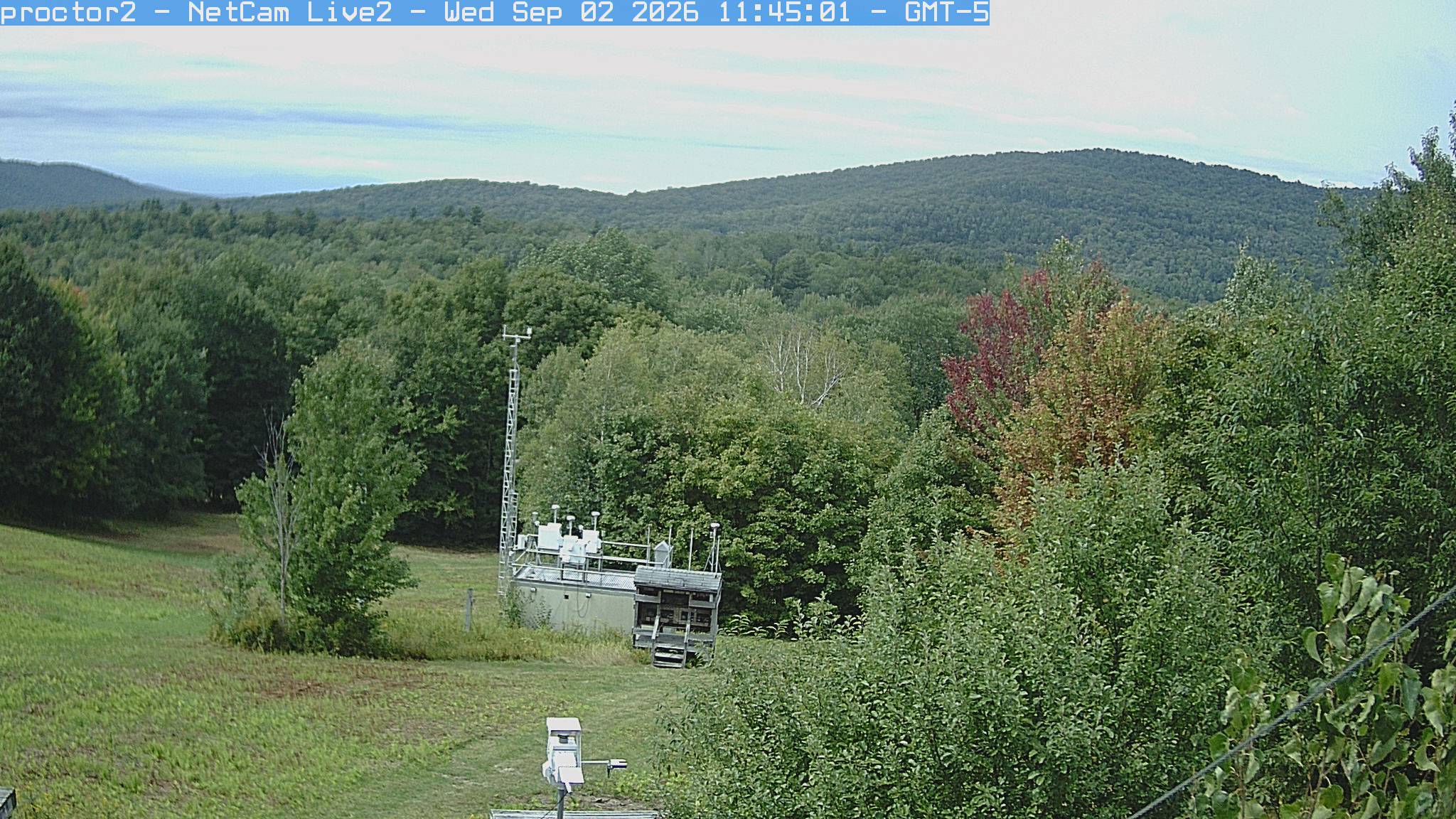 Wooded hills rise beyond an open foreground with research instruments.