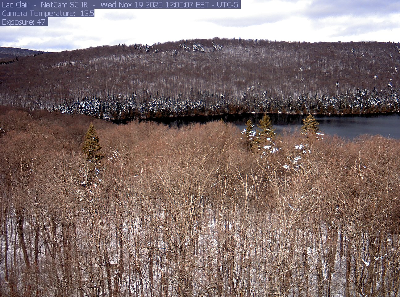 A wooded hillside and close canopy frame the water at Lac Clair.