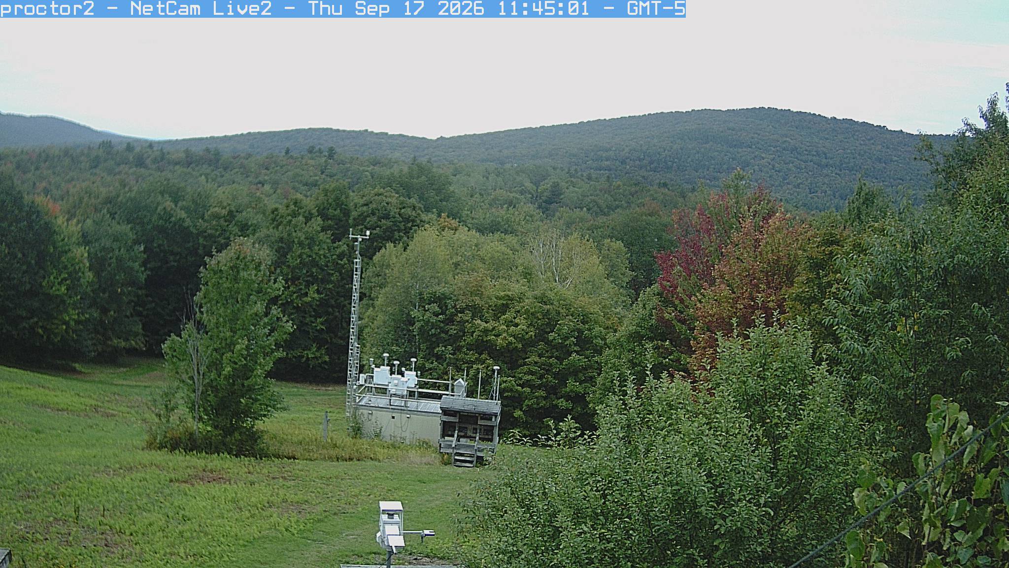Wooded hills rise beyond an open foreground with research instruments.