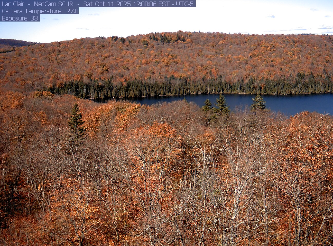 A wooded hillside and close canopy frame the water at Lac Clair.