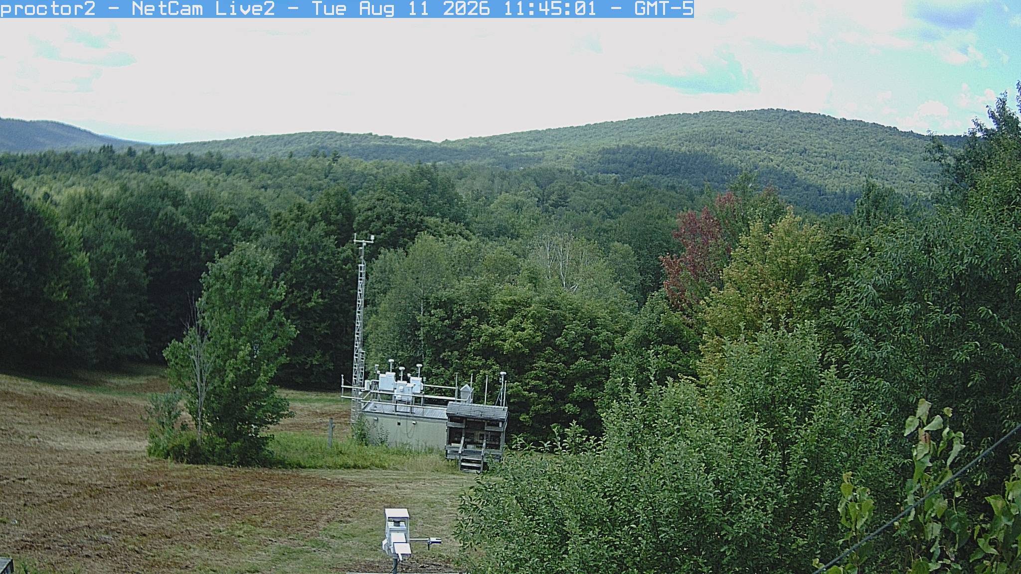 Wooded hills rise beyond an open foreground with research instruments.