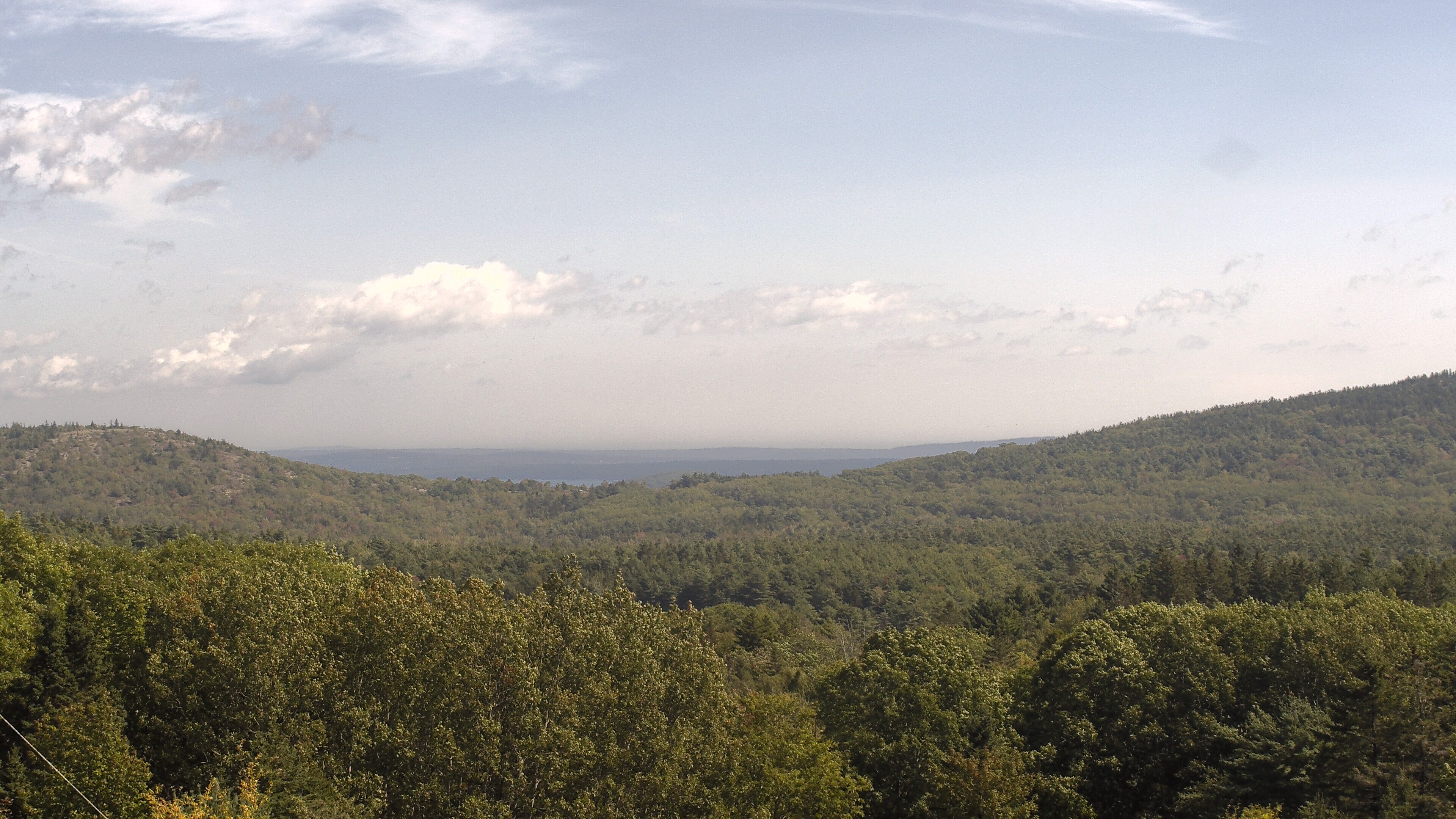 A wooded valley opens toward distant water, seen from McFarland Hill.