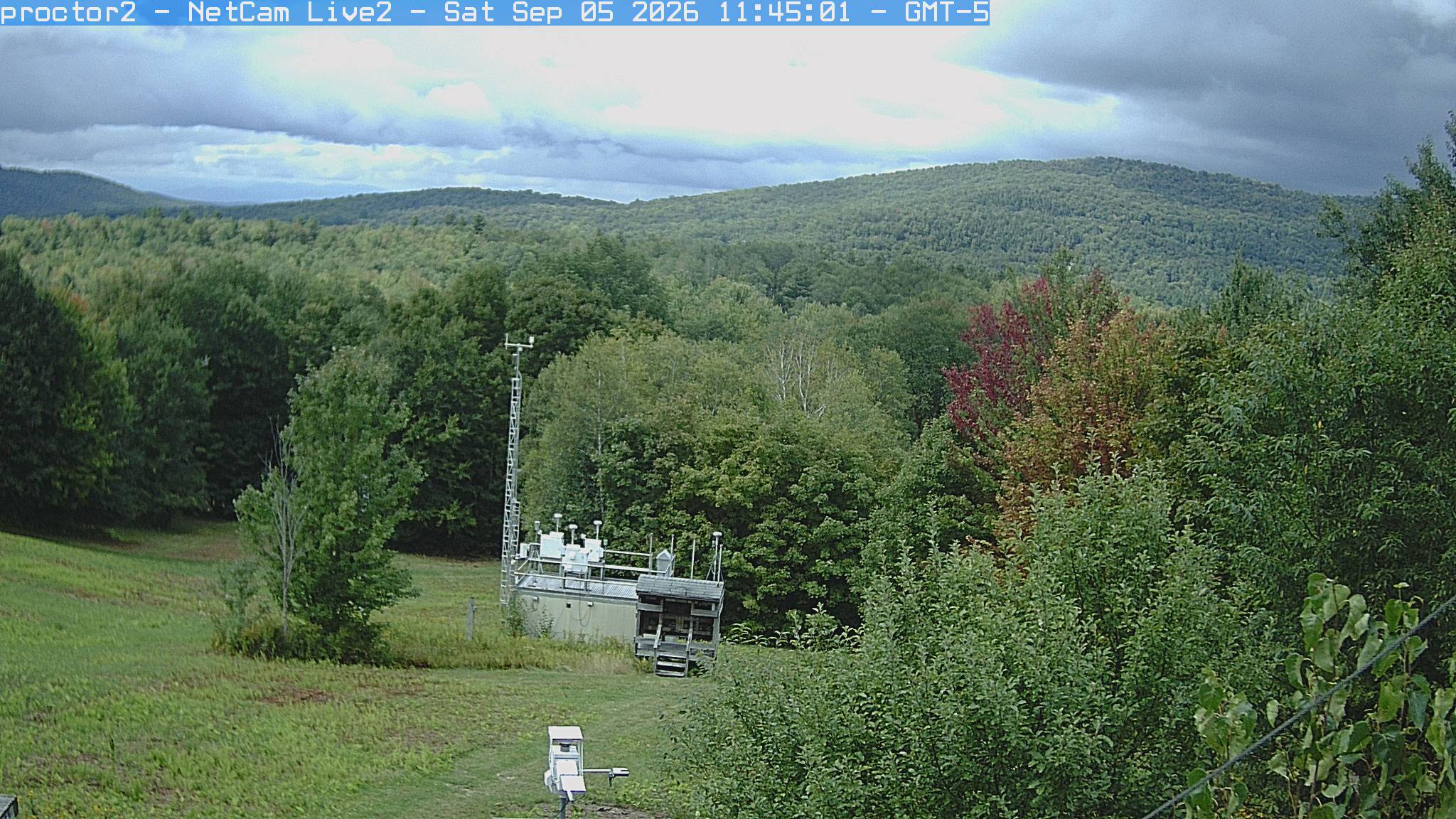 Wooded hills rise beyond an open foreground with research instruments.