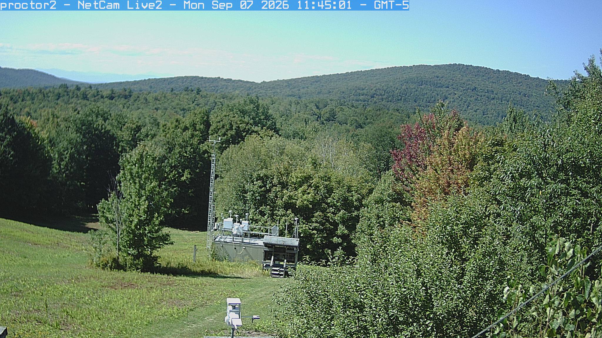 Wooded hills rise beyond an open foreground with research instruments.