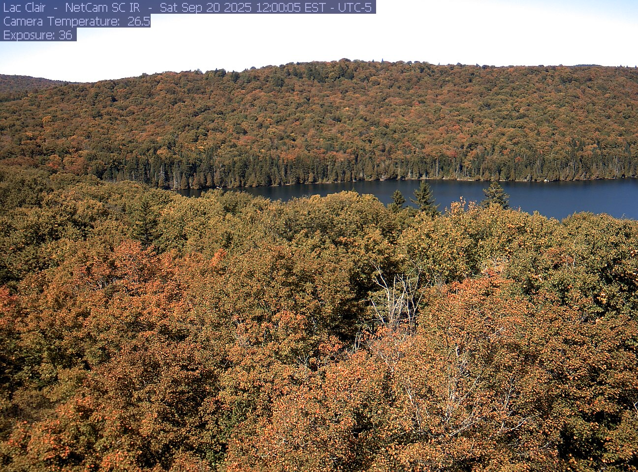 A wooded hillside and close canopy frame the water at Lac Clair.
