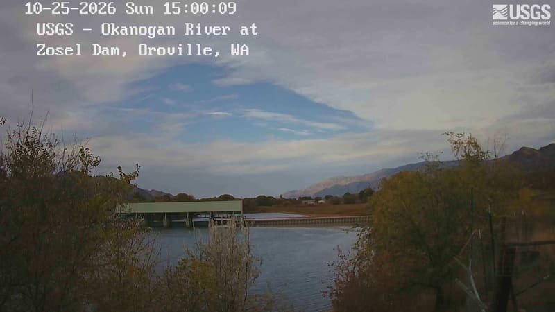 The Okanogan River at the old millpond, golden and orange trees along the bank and dry hills beyond.