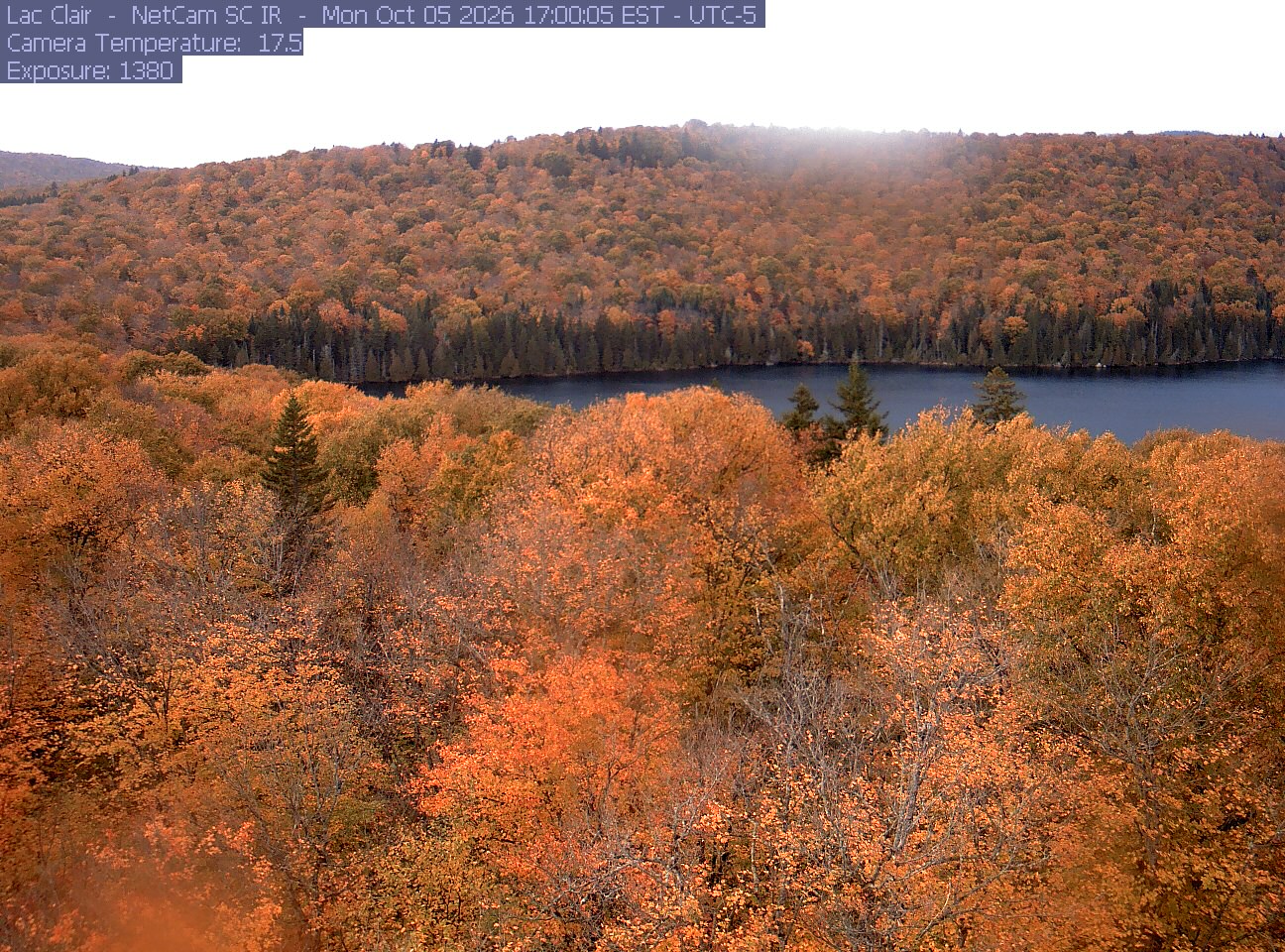 A wooded hillside and close canopy frame the water at Lac Clair.