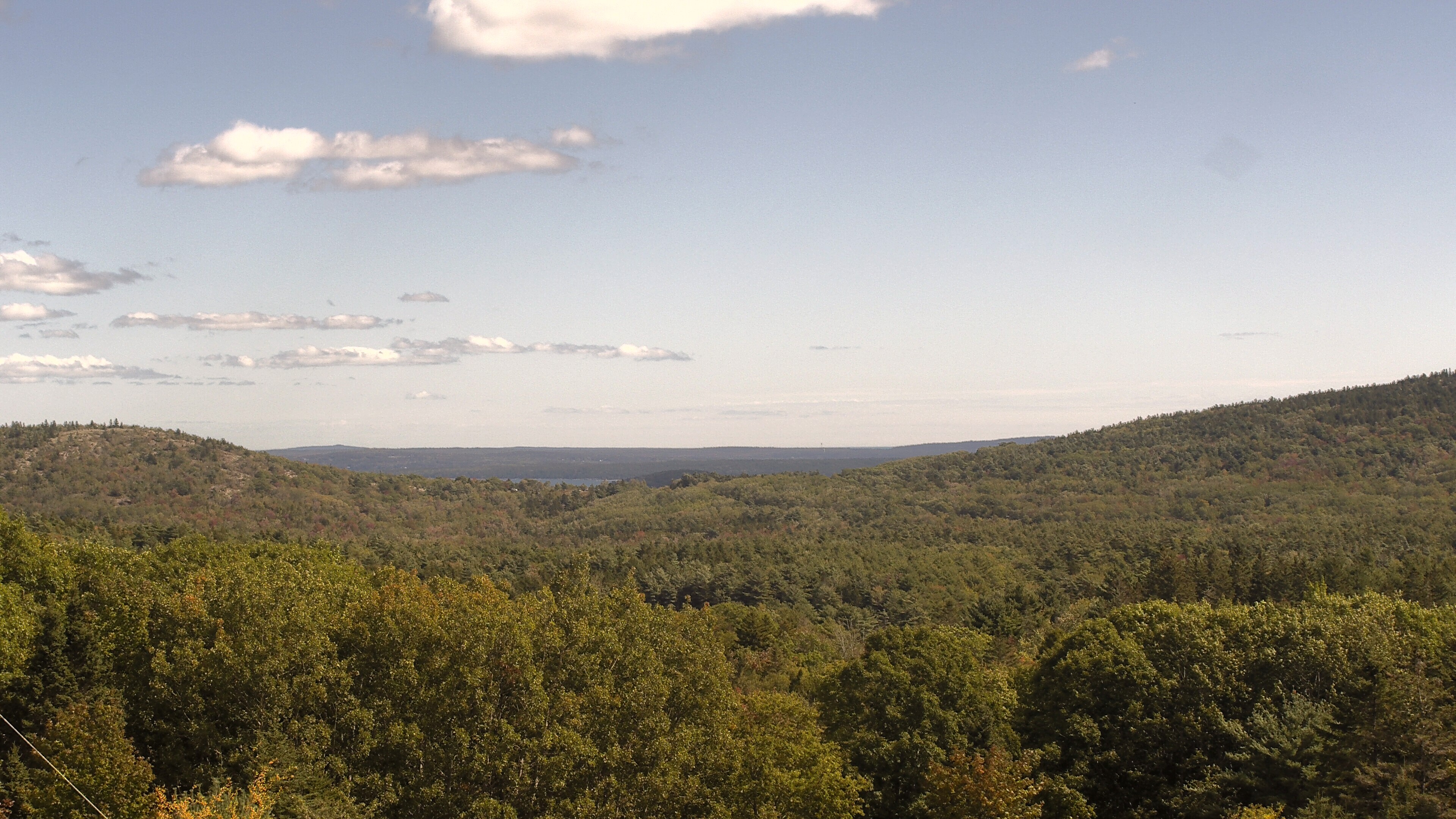 A wooded valley opens toward distant water, seen from McFarland Hill.