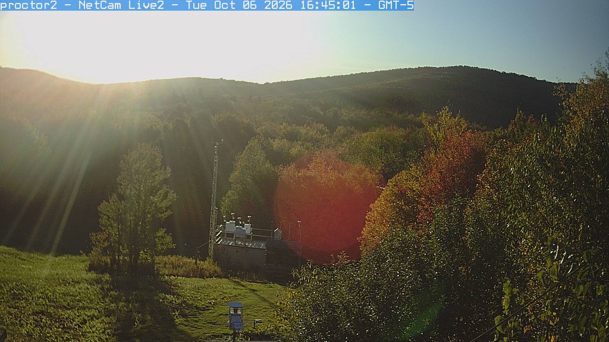Wooded hills rise beyond an open foreground with research instruments.