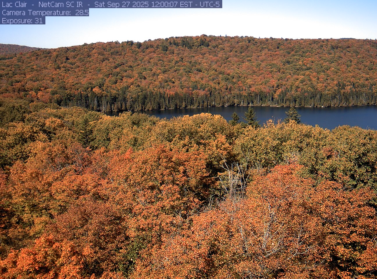 A wooded hillside and close canopy frame the water at Lac Clair.