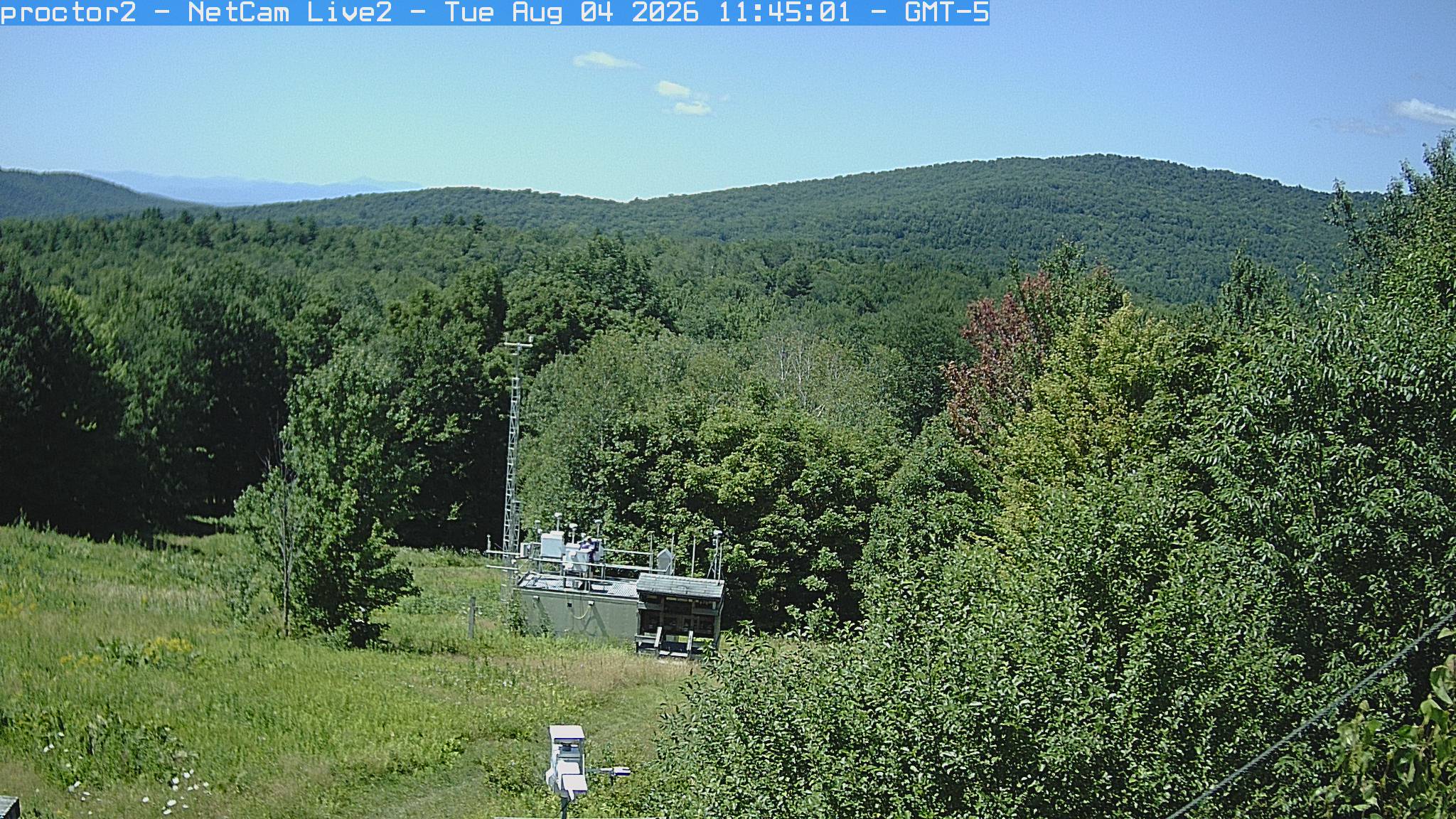 Wooded hills rise beyond an open foreground with research instruments.