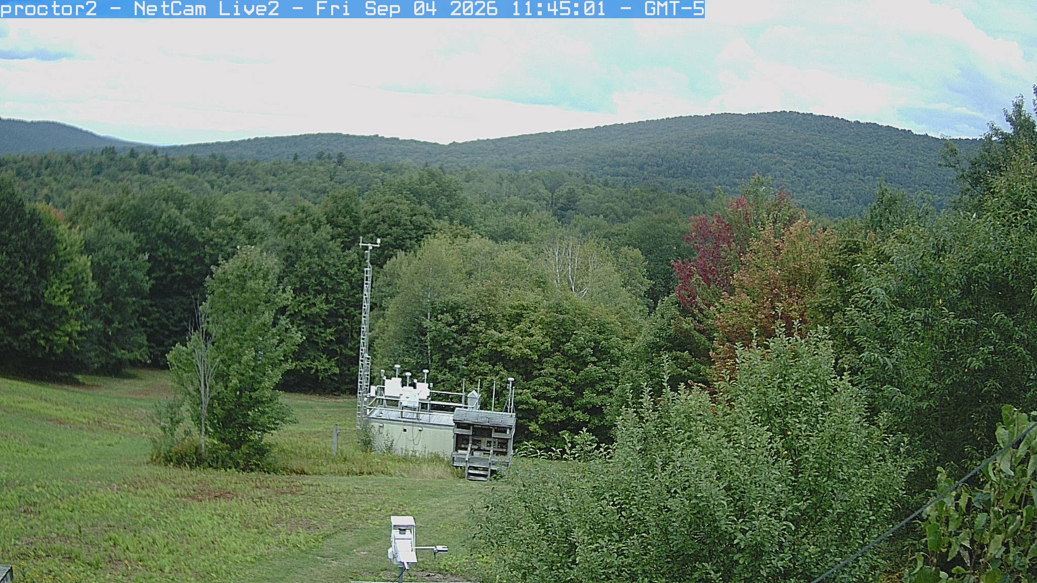 Wooded hills rise beyond an open foreground with research instruments.