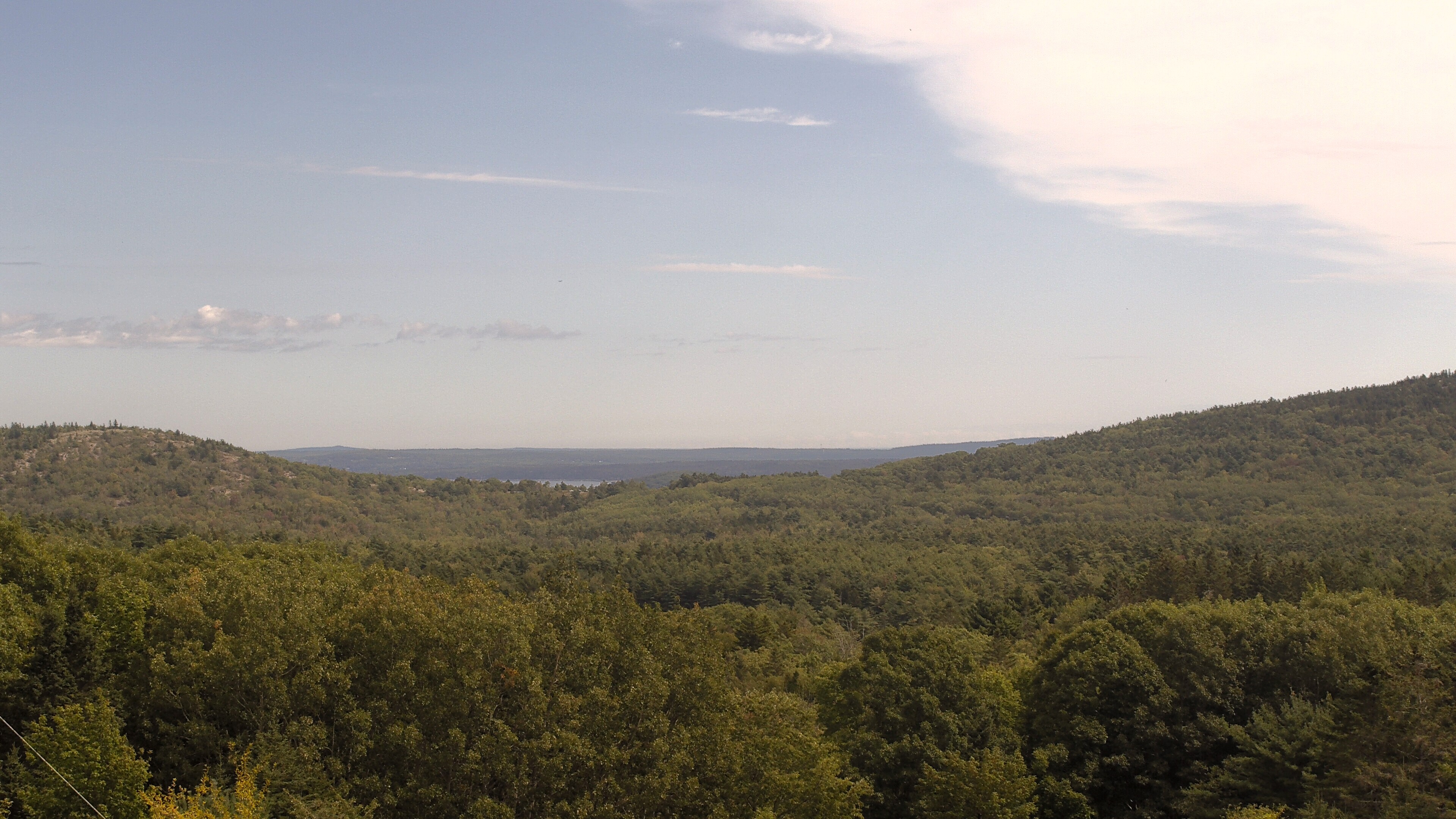 A wooded valley opens toward distant water, seen from McFarland Hill.