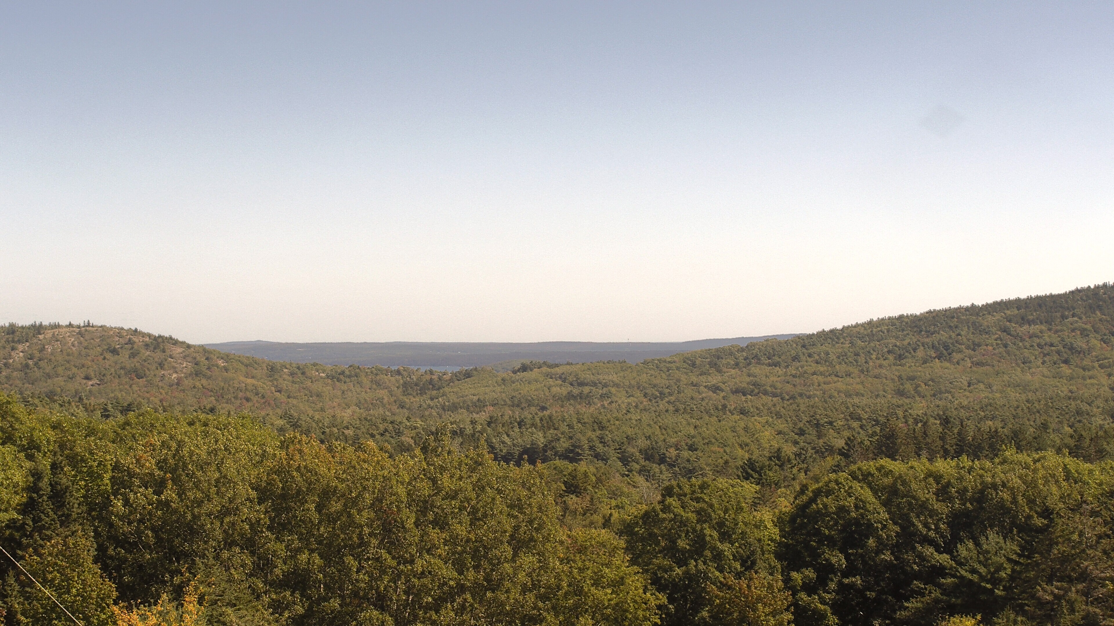 A wooded valley opens toward distant water, seen from McFarland Hill.