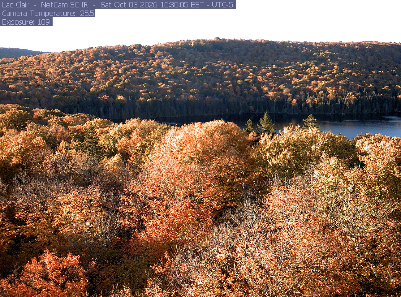 A wooded hillside and close canopy frame the water at Lac Clair.