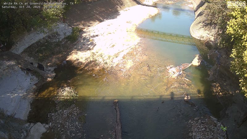 White Rock Creek runs low over pale stone below a footbridge, with trees along the right bank.