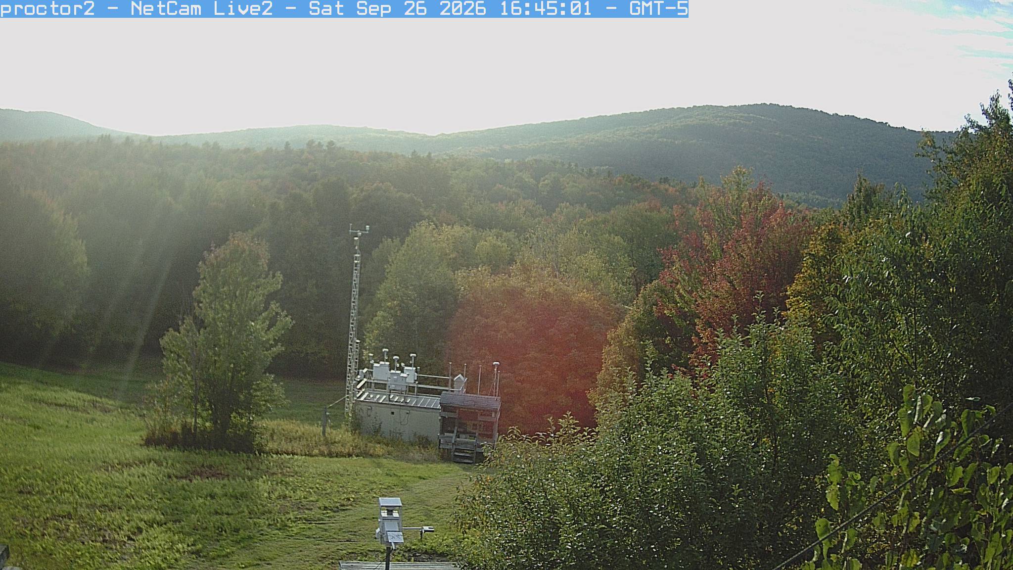 Wooded hills rise beyond an open foreground with research instruments.