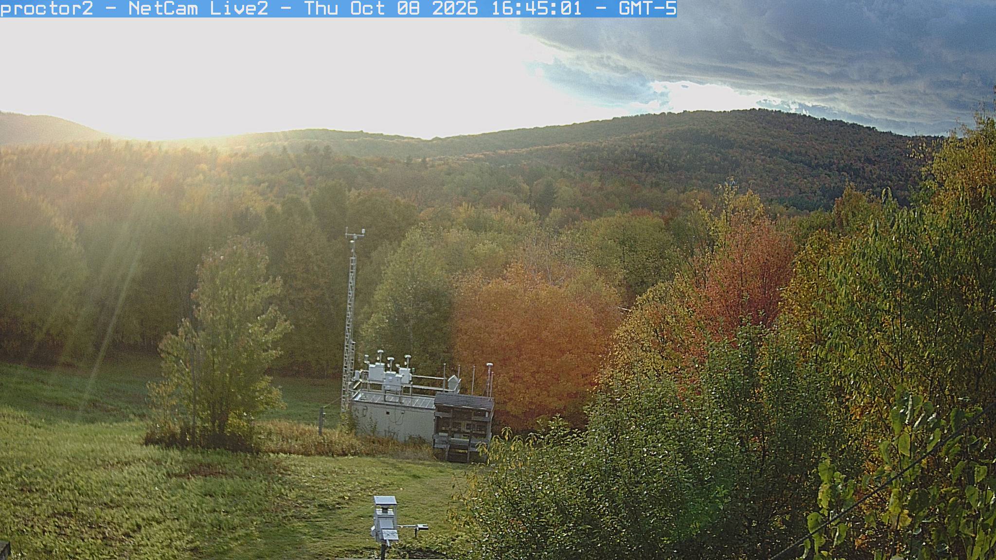 Wooded hills rise beyond an open foreground with research instruments.