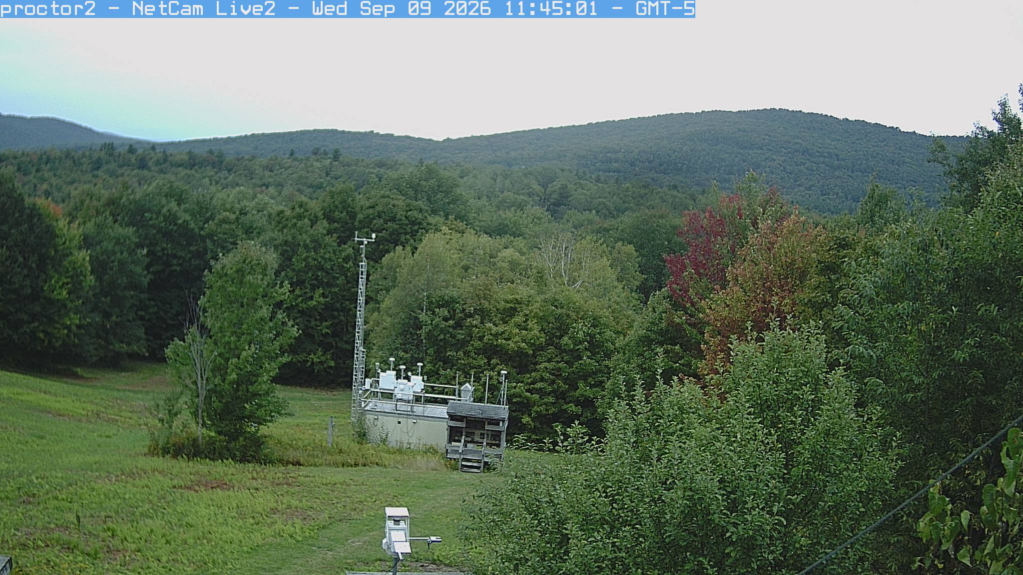 Wooded hills rise beyond an open foreground with research instruments.