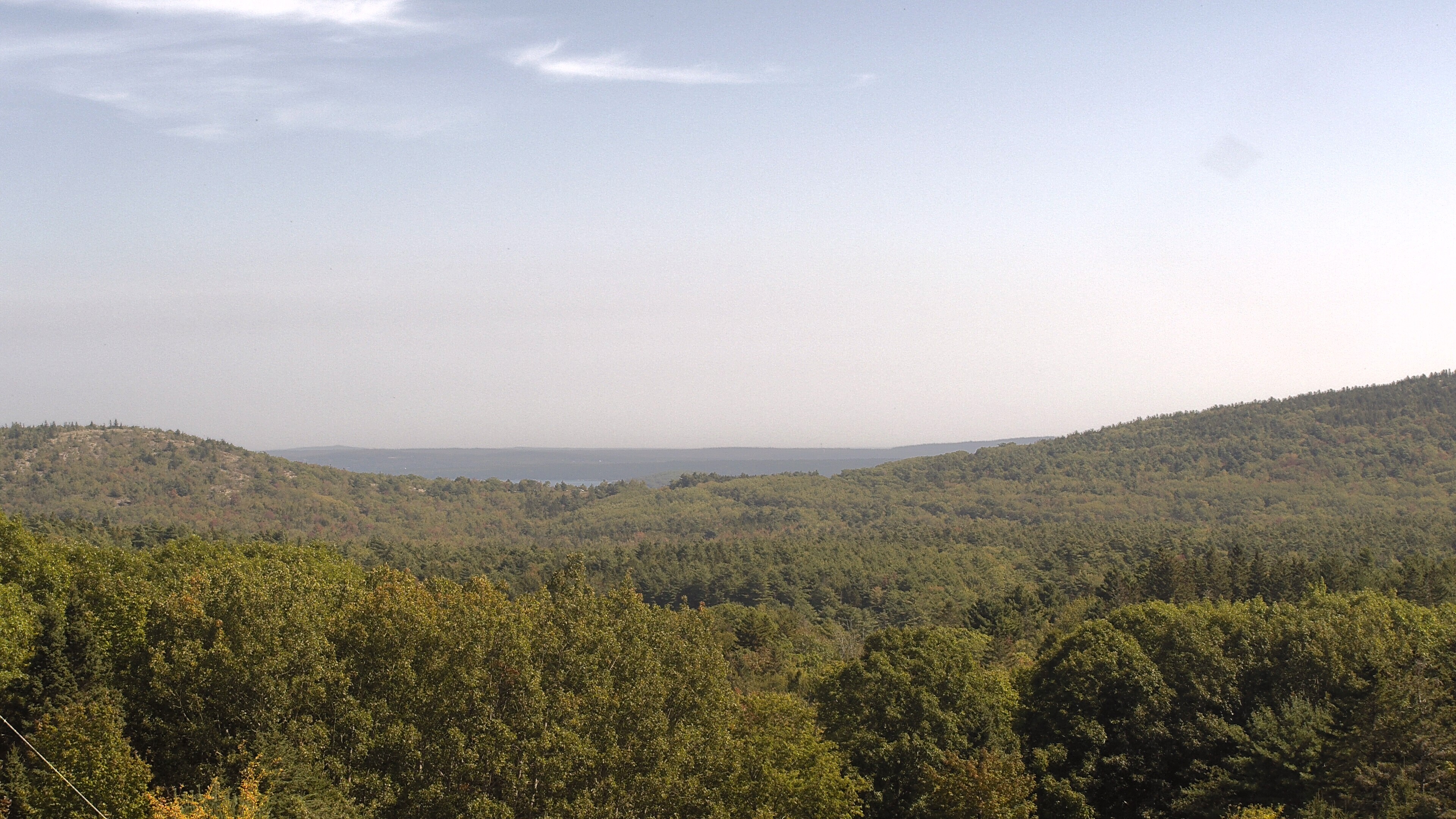 A wooded valley opens toward distant water, seen from McFarland Hill.