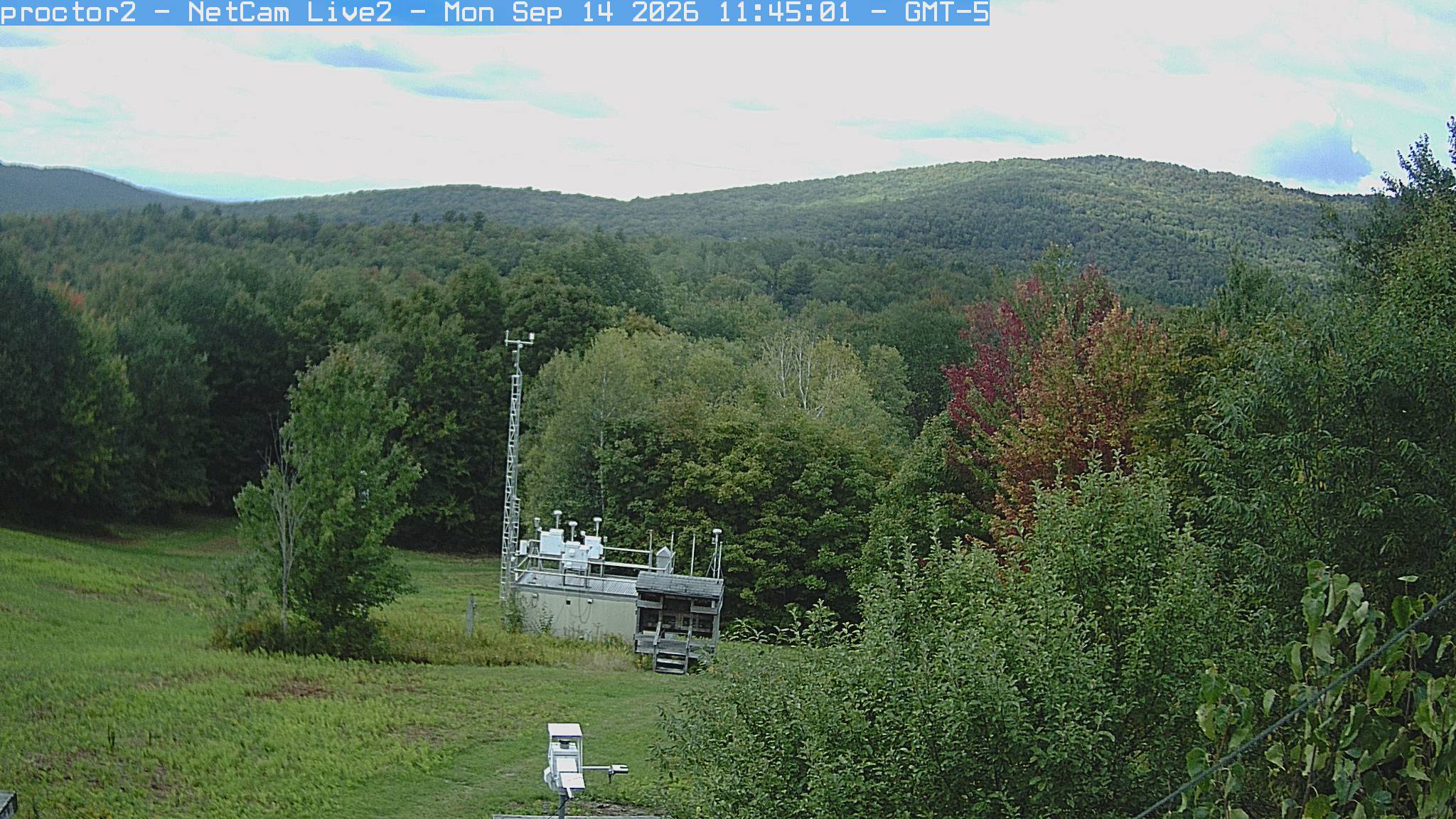 Wooded hills rise beyond an open foreground with research instruments.