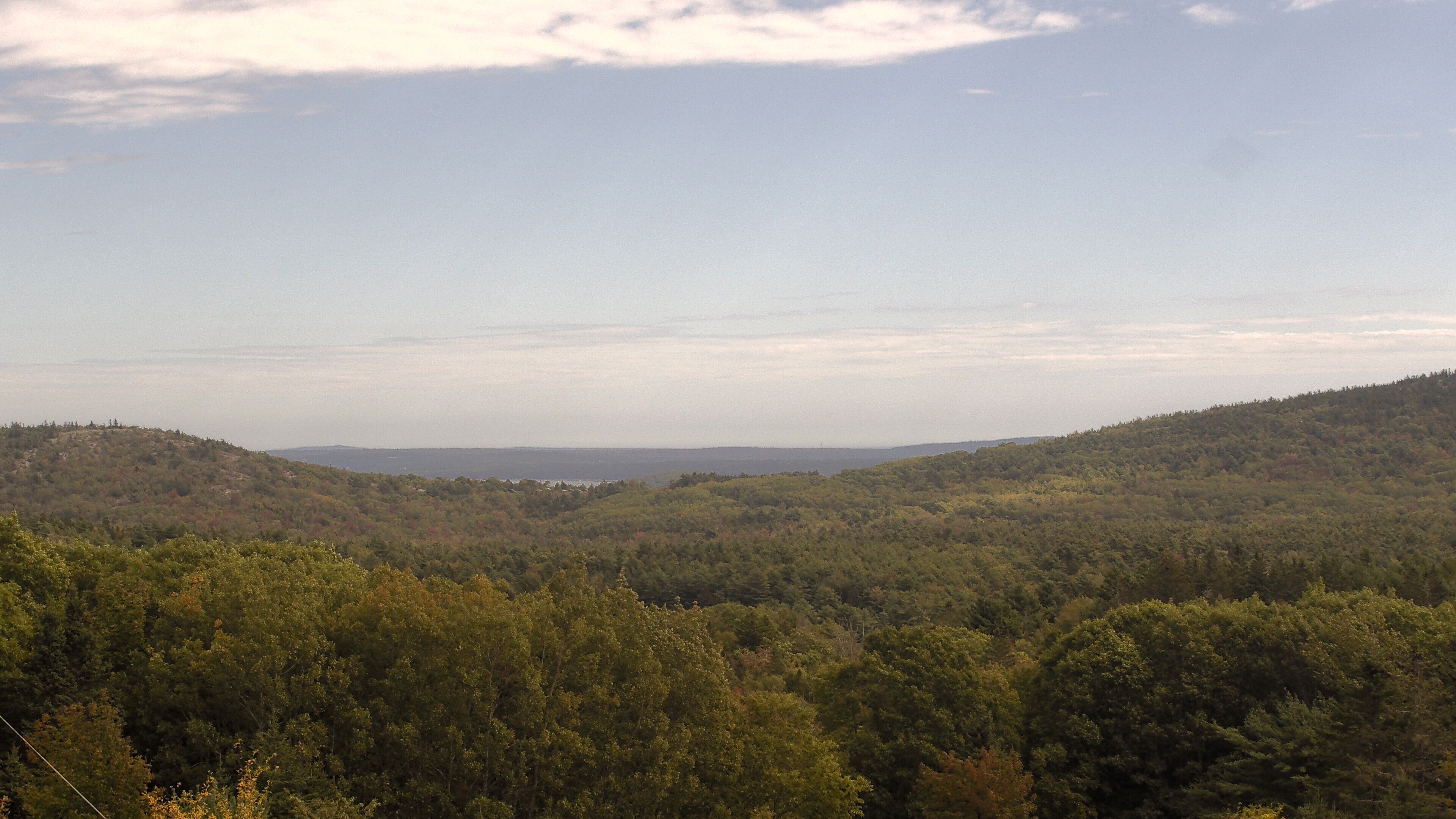A wooded valley opens toward distant water, seen from McFarland Hill.
