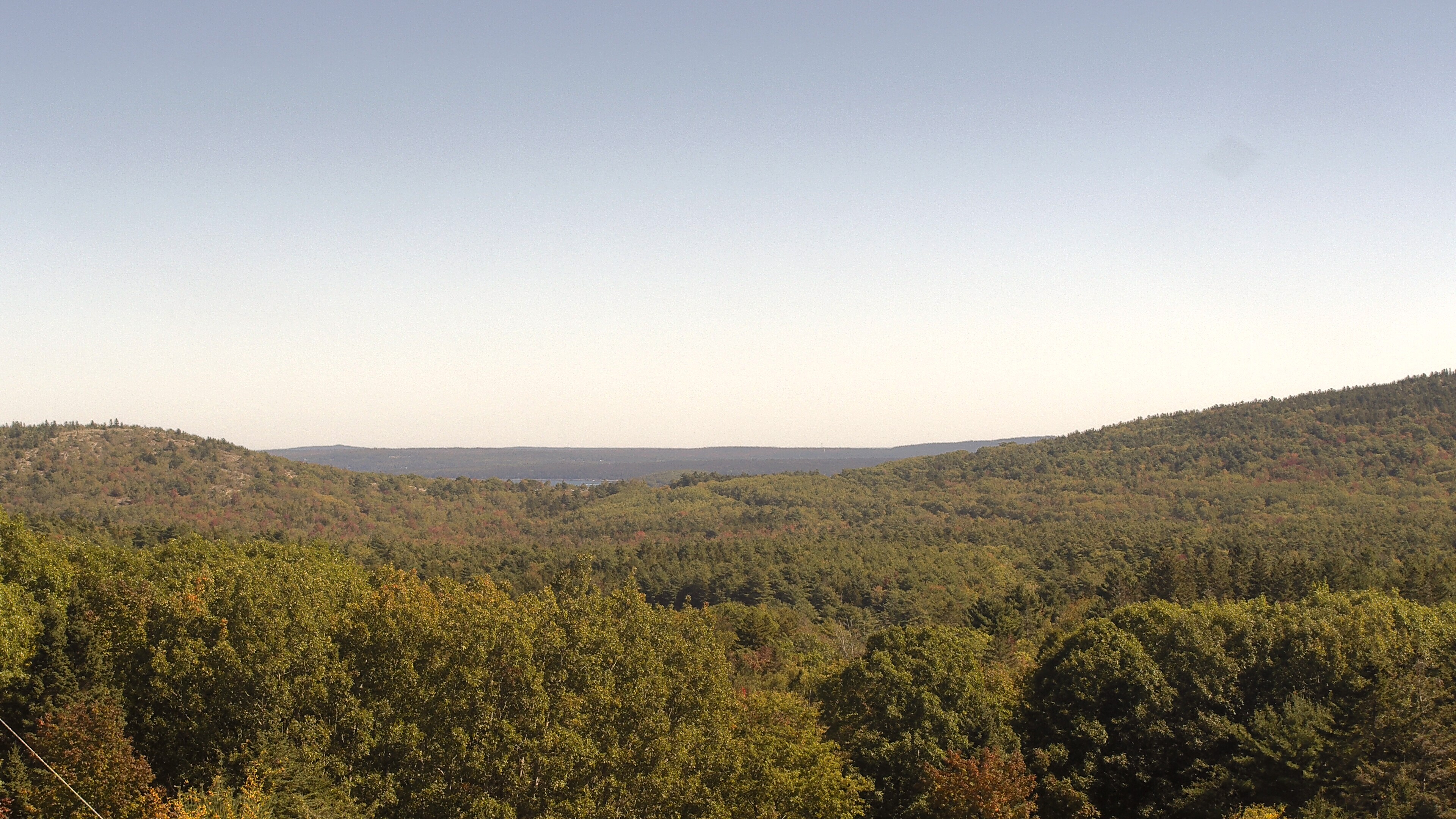 A wooded valley opens toward distant water, seen from McFarland Hill.