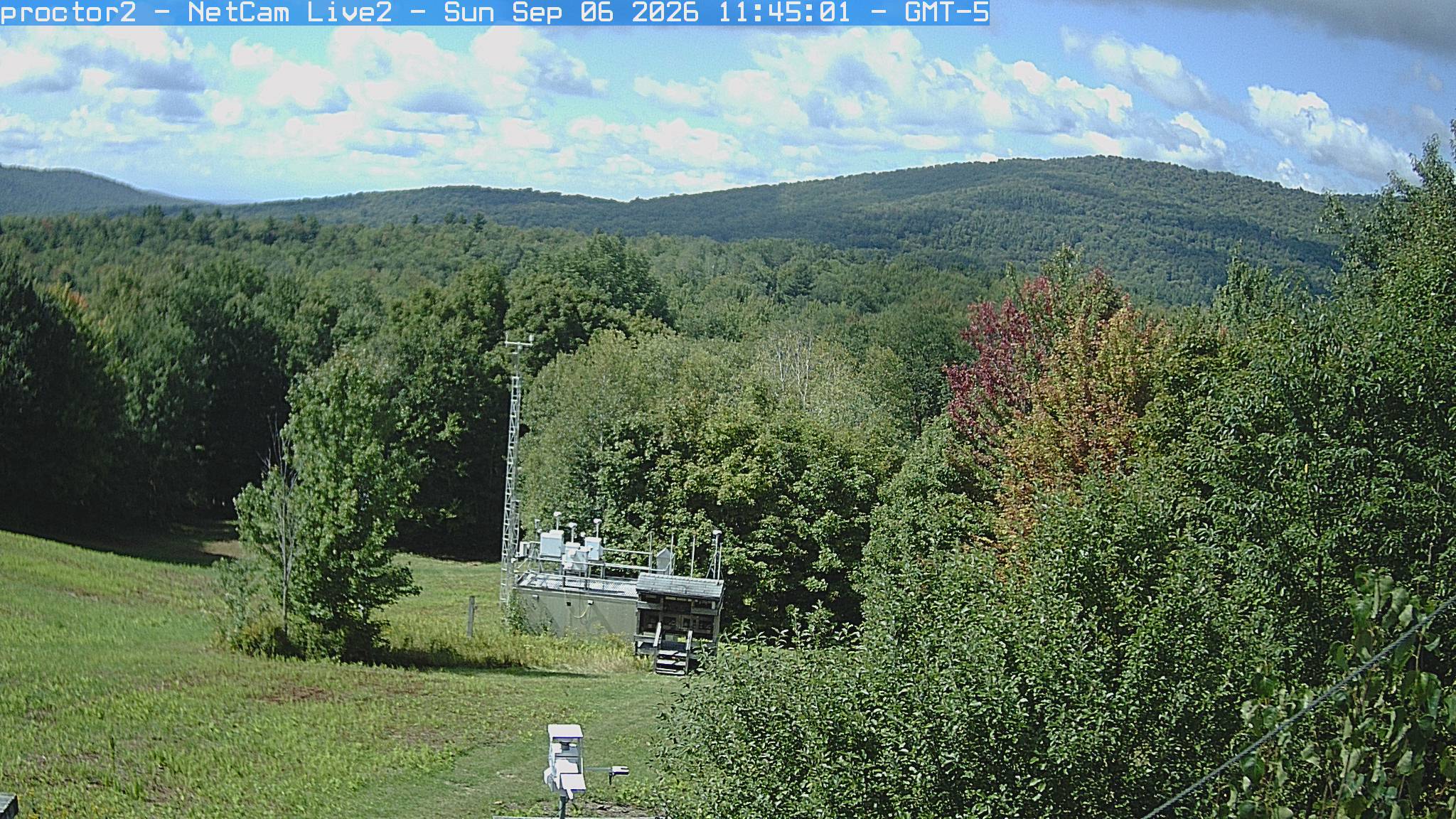 Wooded hills rise beyond an open foreground with research instruments.