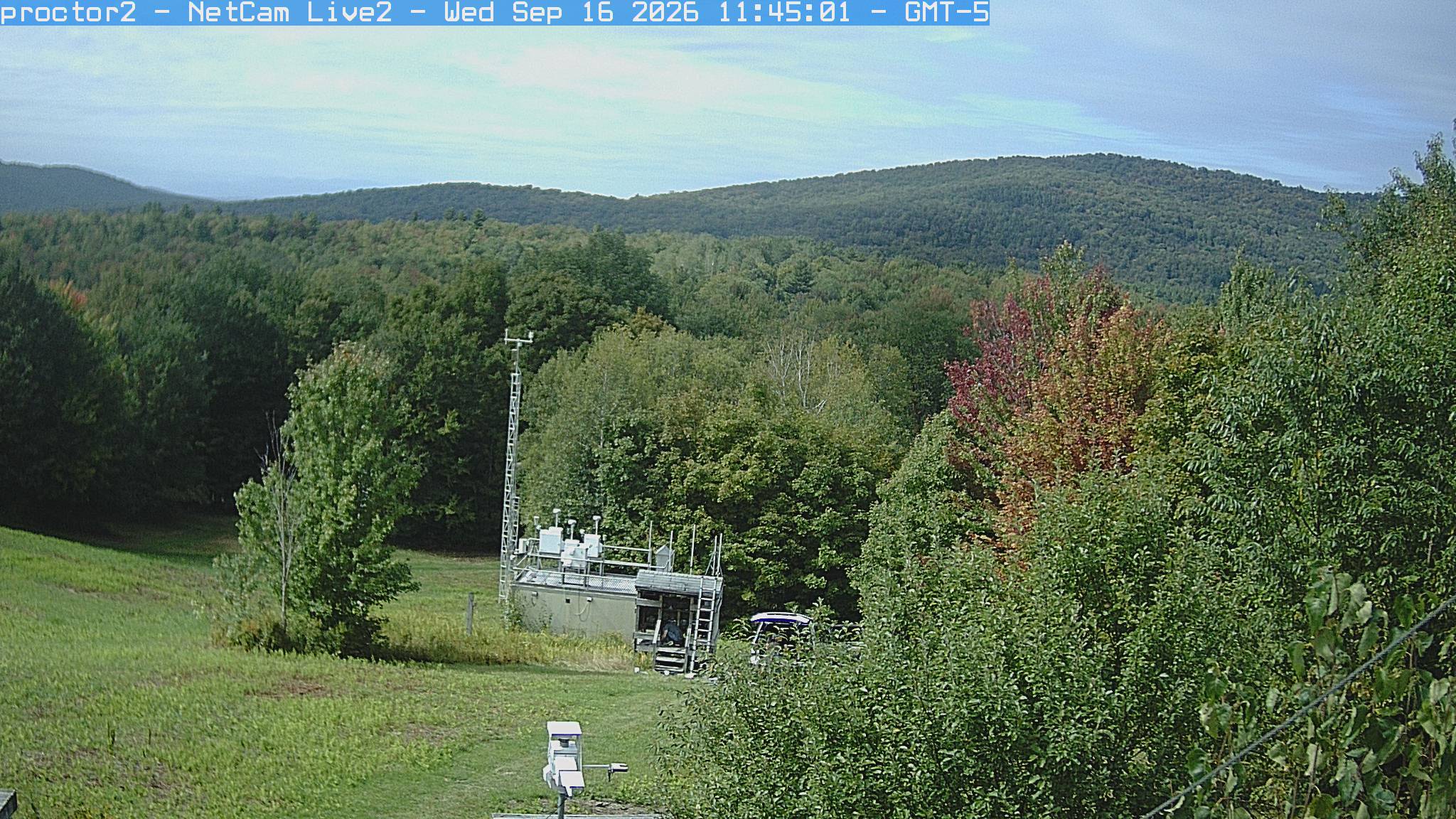 Wooded hills rise beyond an open foreground with research instruments.