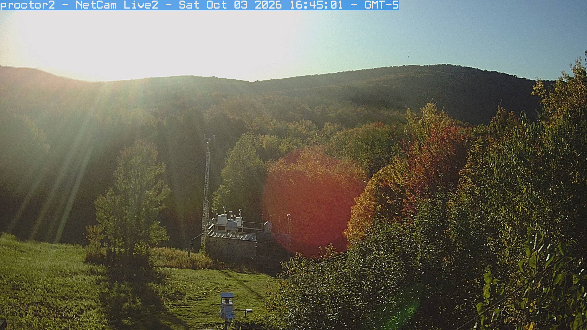 Wooded hills rise beyond an open foreground with research instruments.