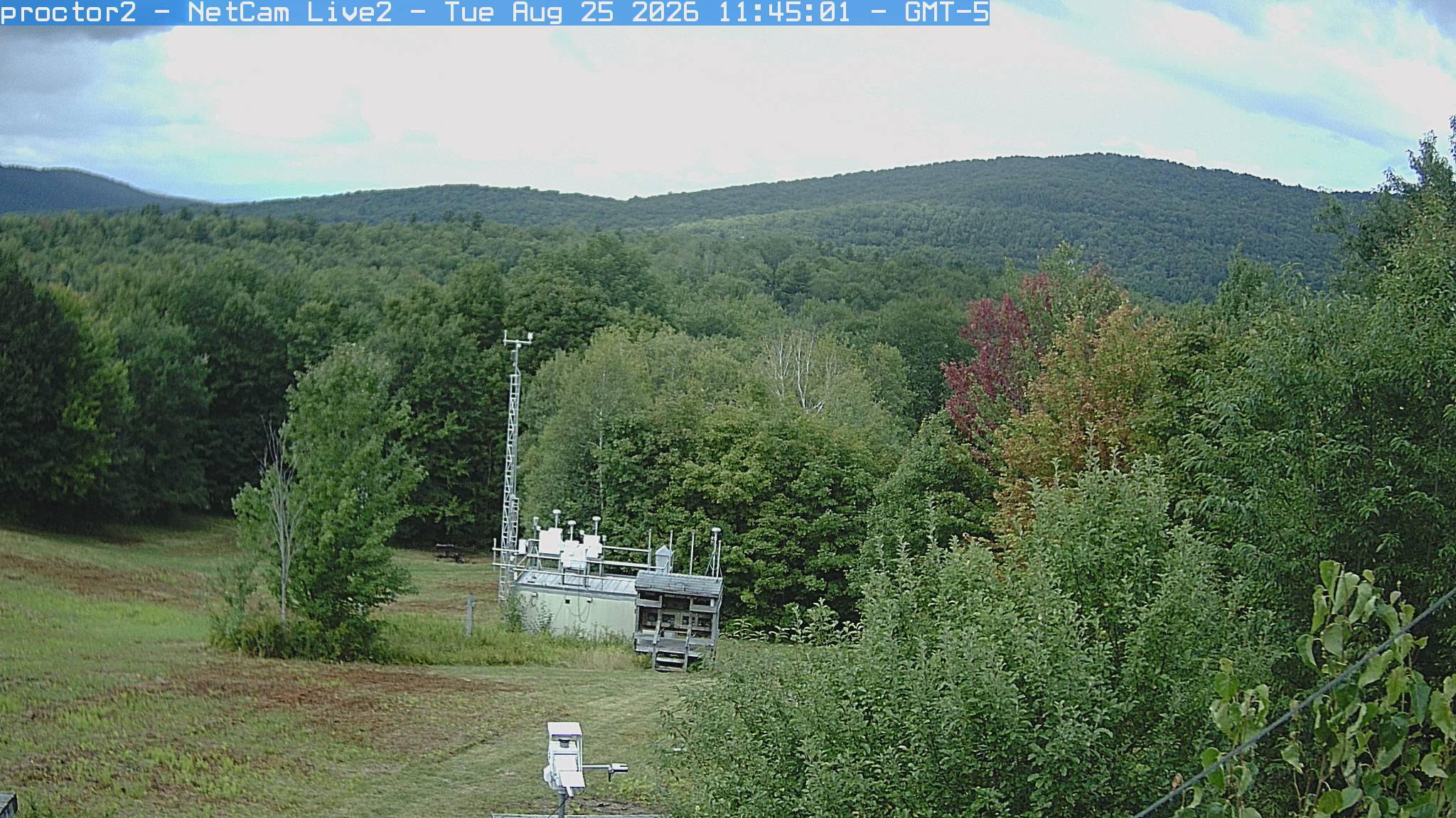 Wooded hills rise beyond an open foreground with research instruments.