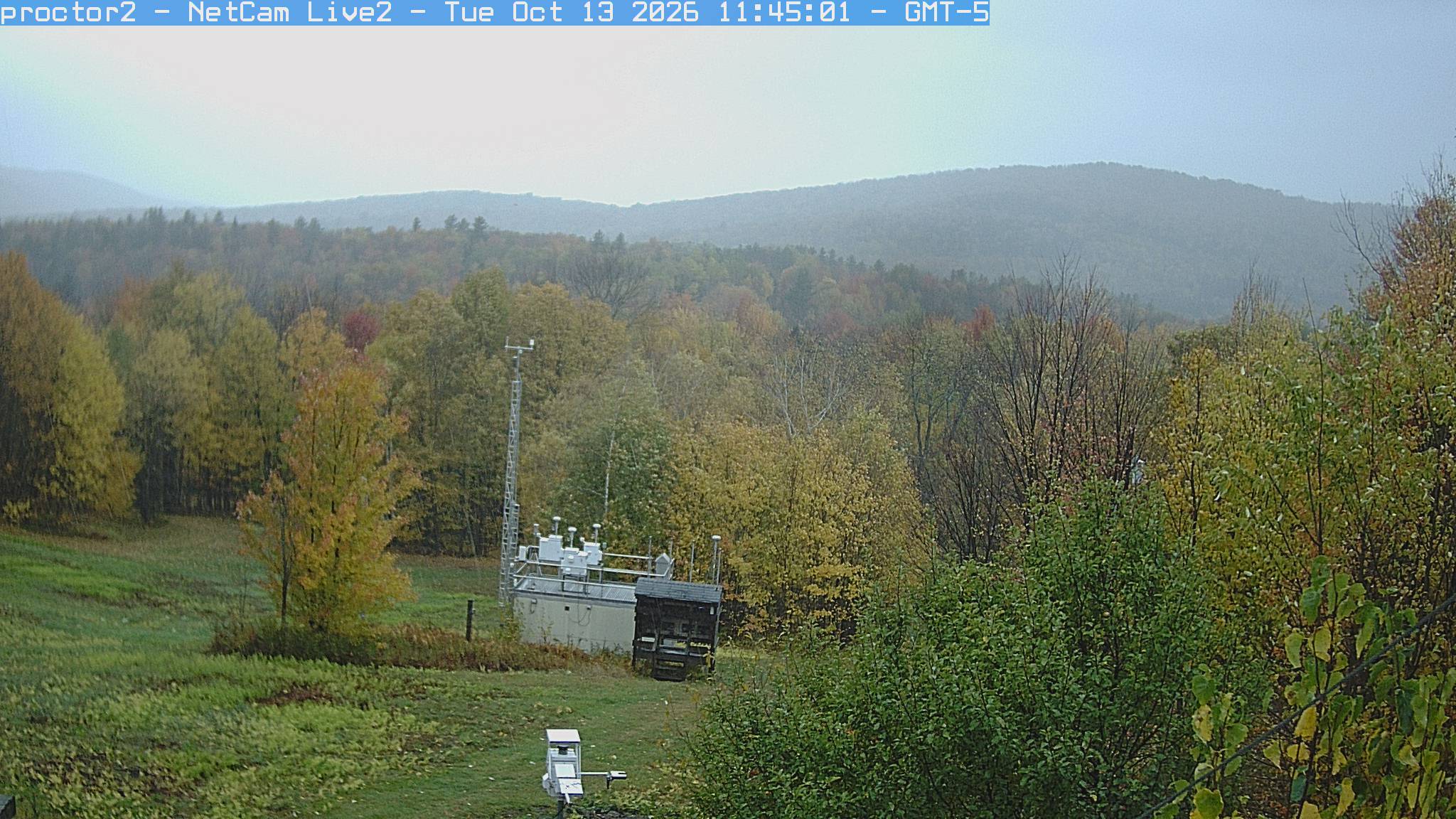 Wooded hills rise beyond an open foreground with research instruments.