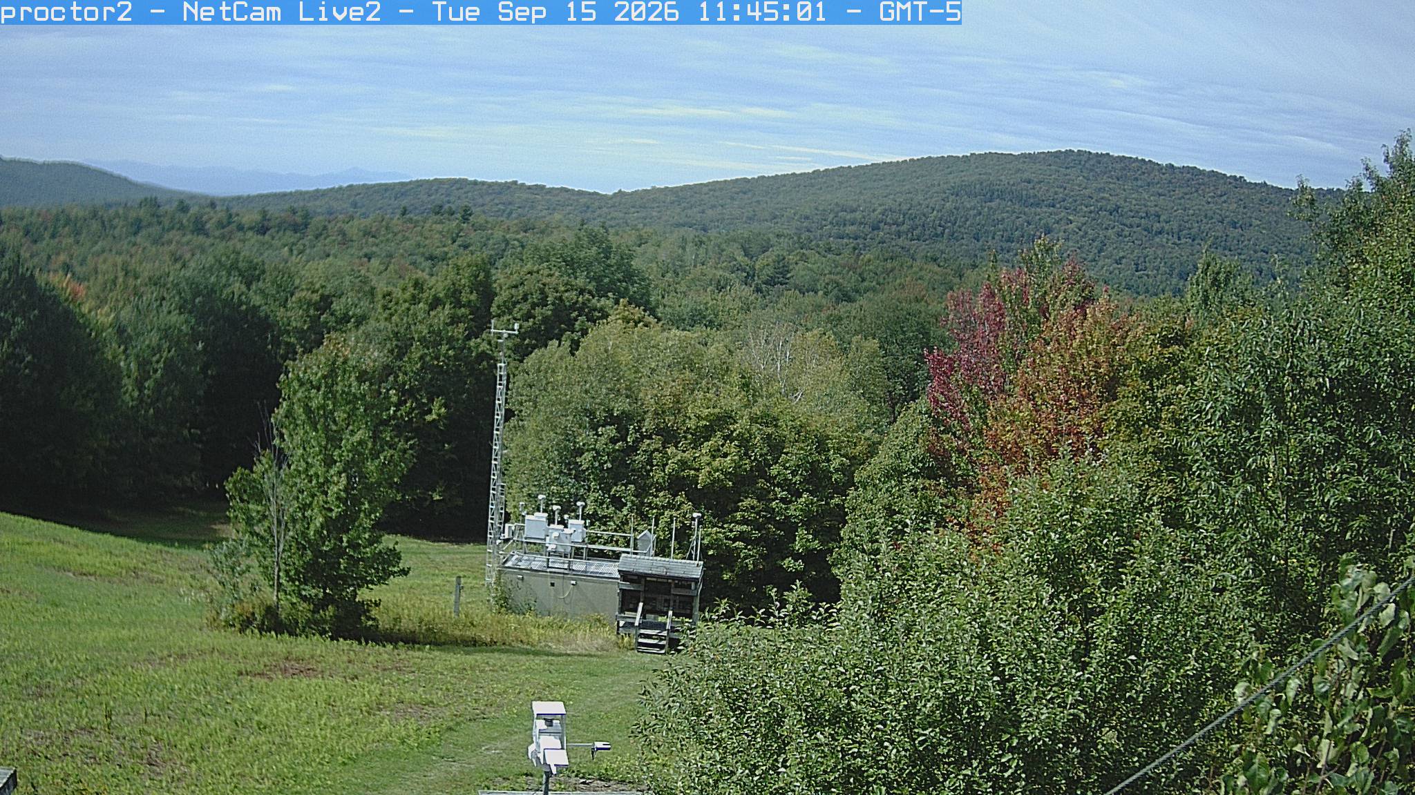 Wooded hills rise beyond an open foreground with research instruments.