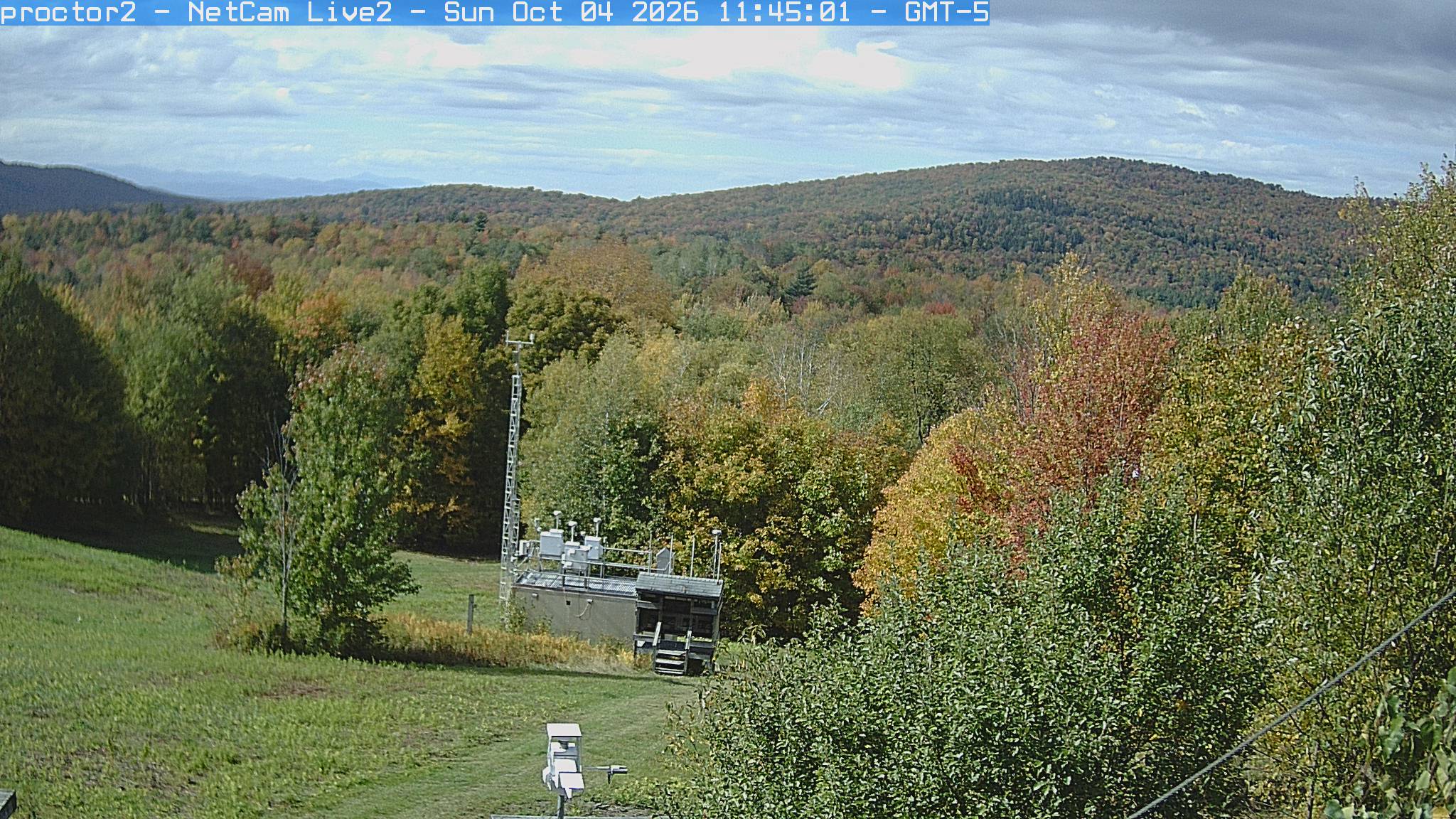 Wooded hills rise beyond an open foreground with research instruments.